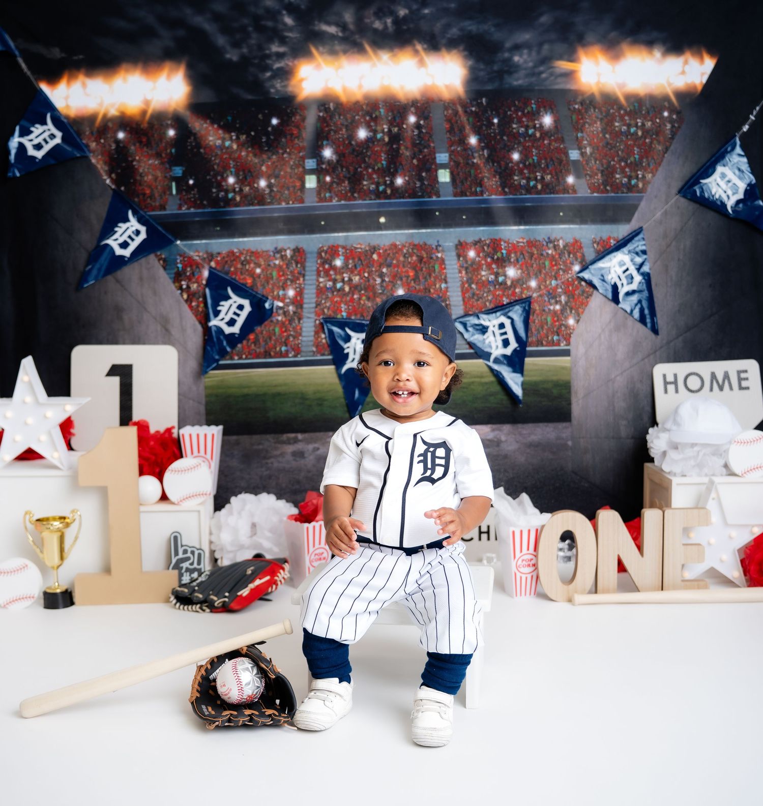 Metro Detroit children photographer Detroit Tigers baseball themed photo setup with stadium backdrop and team jersey.