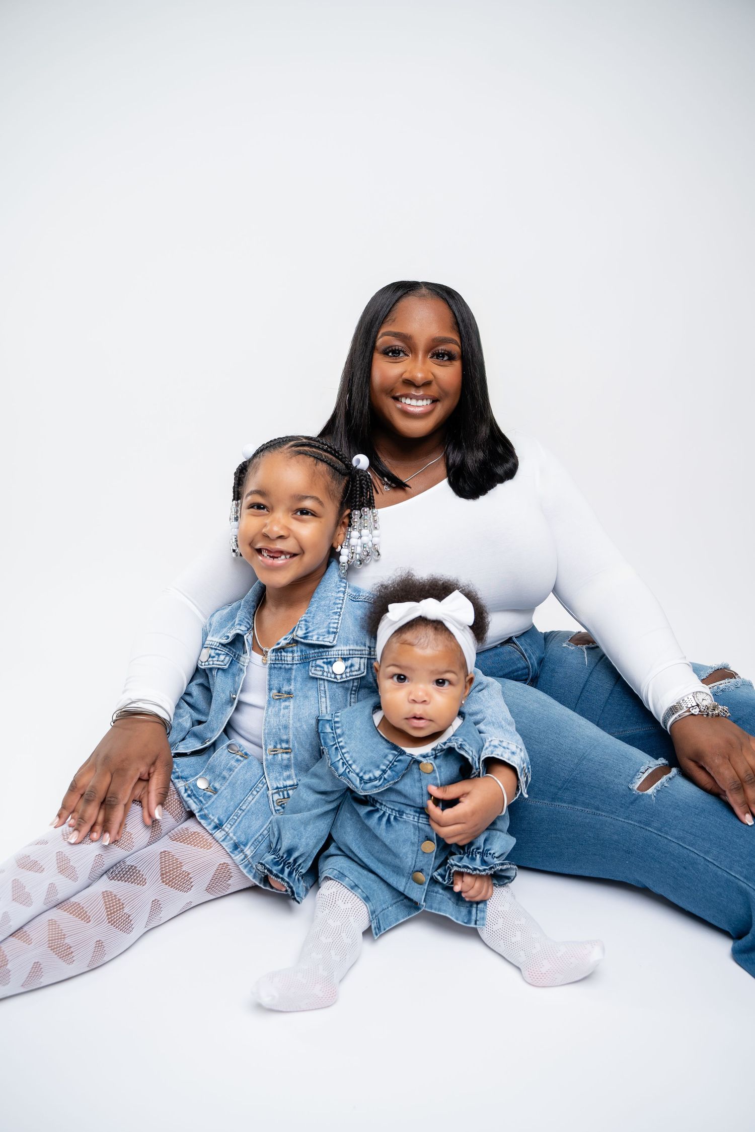 Metro Detroit family photographer capturing Family members in matching denim outfits lay on white background during studio photoshoot.