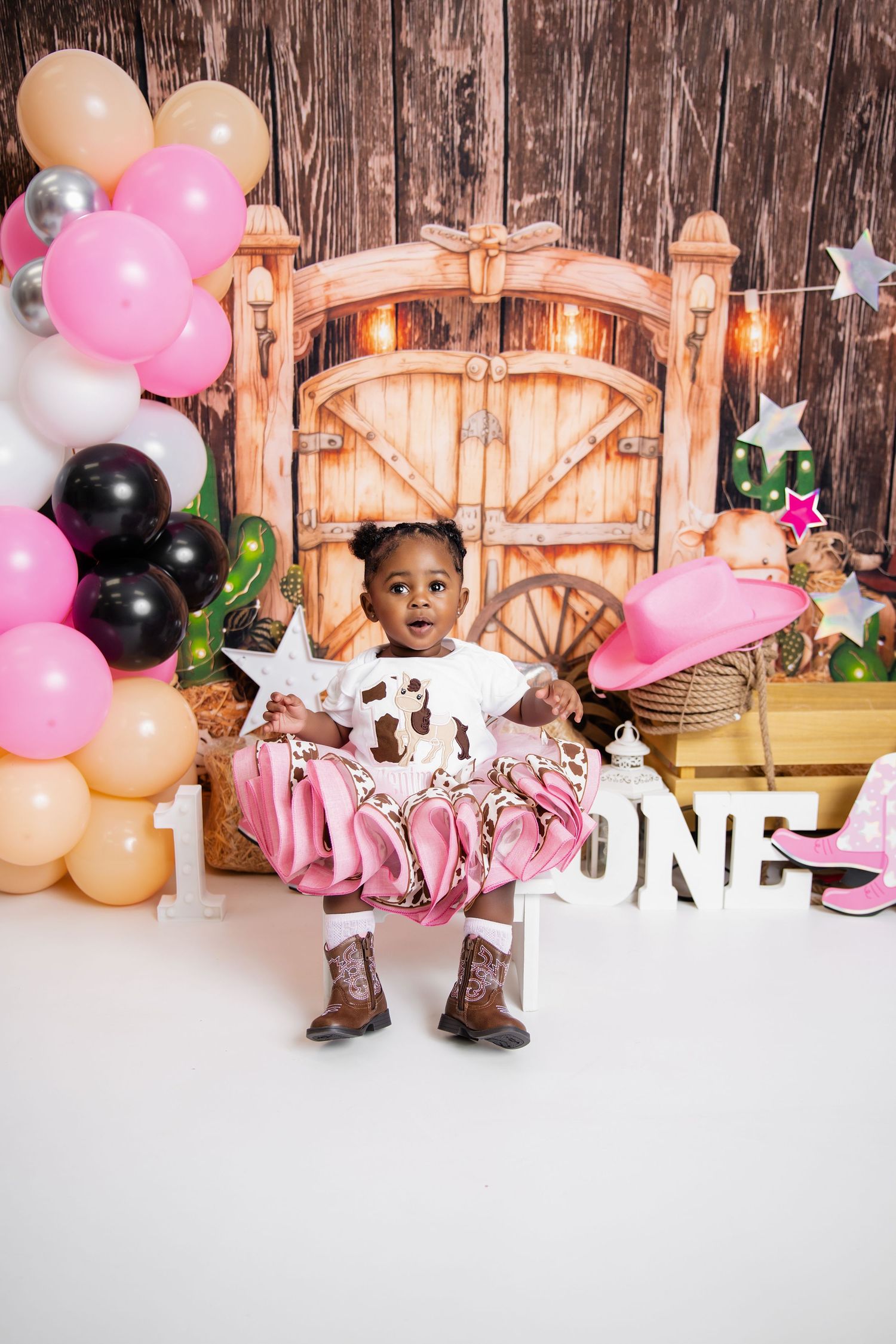 Metro Detroit children photographer photographing toddler in studio First birthday party setup with rustic wooden backdrop