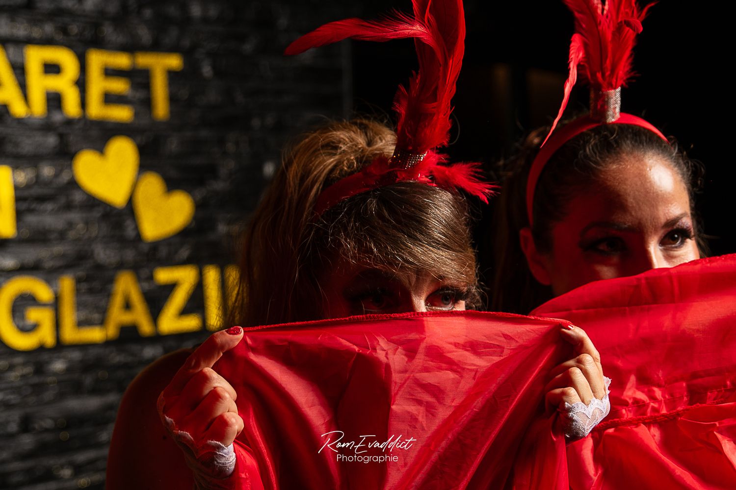 deux danseuse de cancan robe rouge et coiffe plumes rouges se cachant le visage avec leur robe - photocall événement cabaret in glazik