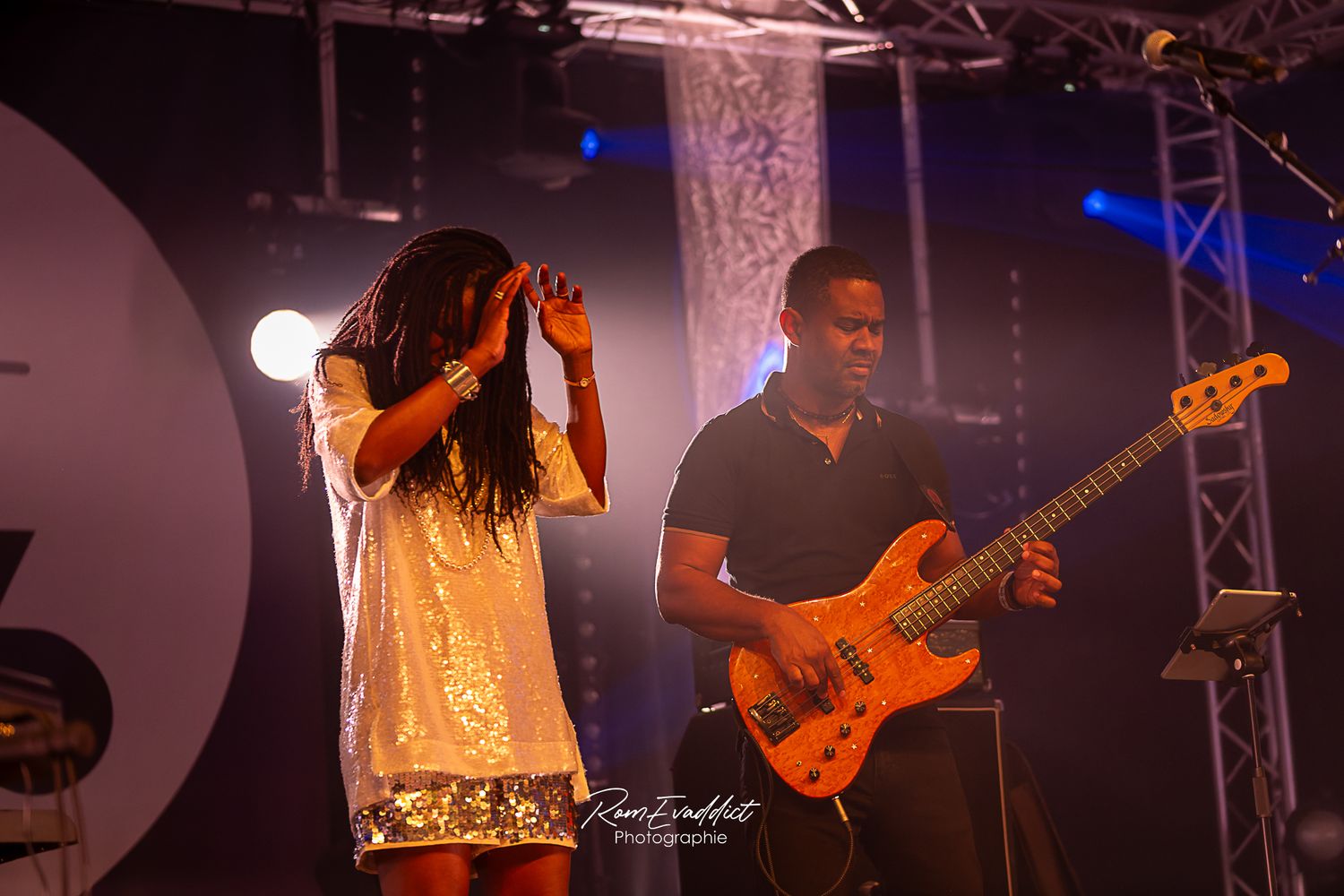 Femme créole chanteuse en robe courte à paillette blanche près de son guitariste durant concert de jazz- photo spectacle événementiel