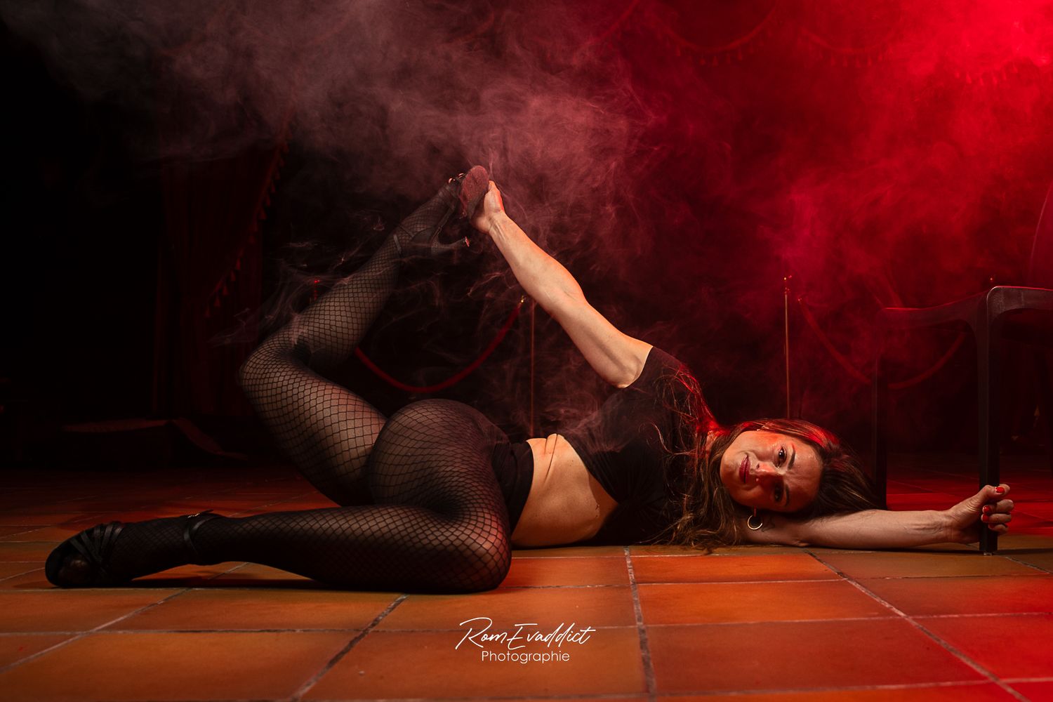 femme danseuse heels broadway en collant et top noir, talons noirs- allongée au sol tenant- ombre et éclairage rouge-portrait boudoir
