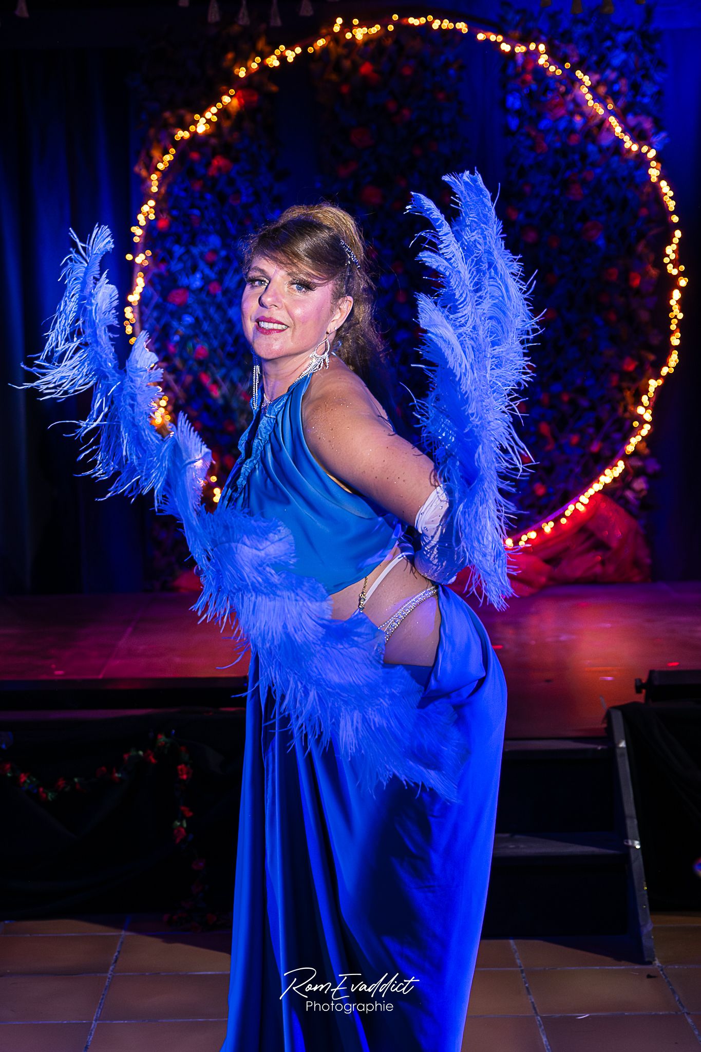 Femme danseuse effeuilleuse burlesque debout sur scène- grande robe bleu avec - éventails en plumes bleues - photo spectacle cabaret