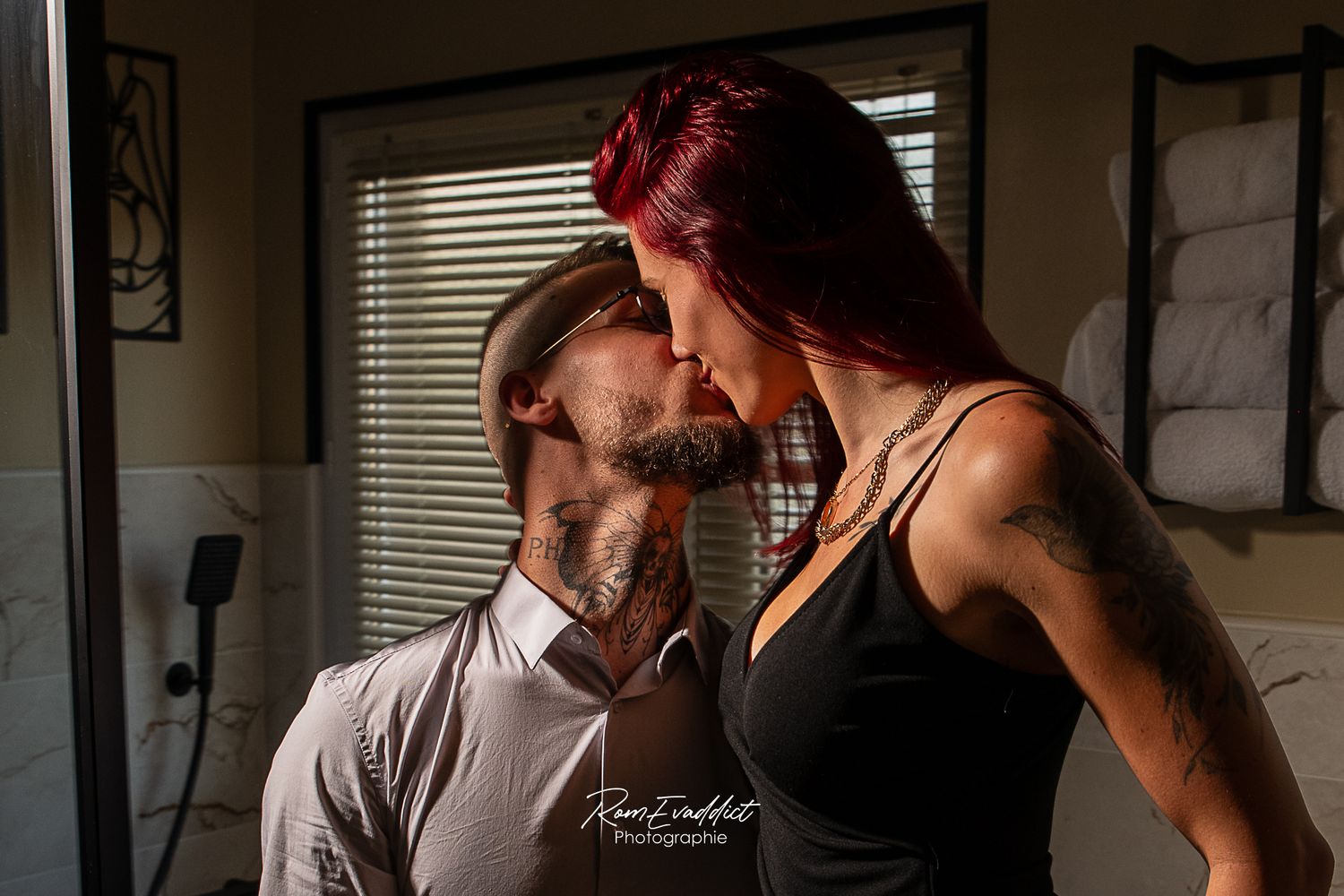 couple s'embrassant dans un éclairage style cinéma-femme cheveux rouge robe noire-homme cheveux courts chemise clair-portrait boudoir