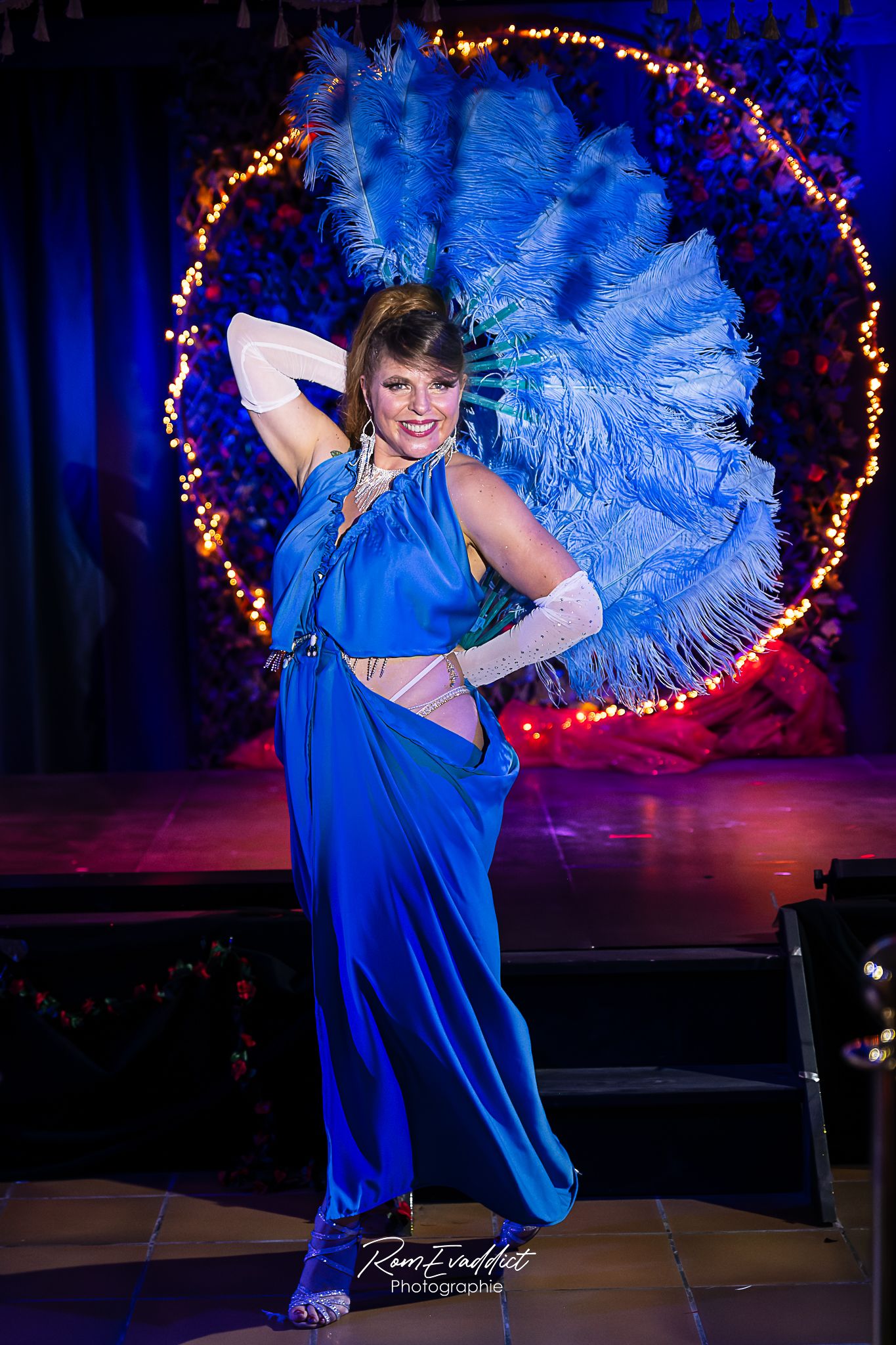 Femme danseuse effeuilleuse burlesque debout sur scène- grande robe bleu avec - éventails en plumes bleues - photo spectacle cabaret