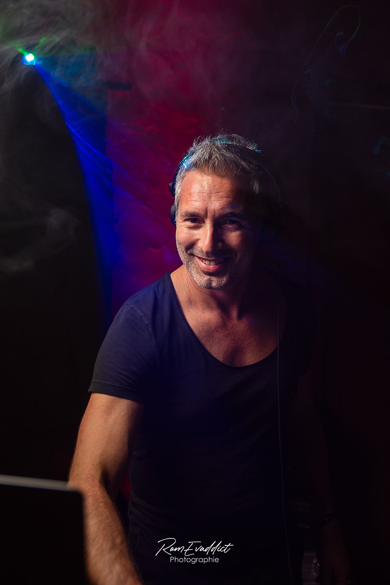photo homme DJ T shirt noir devant platines - fond sombre halo rouge et laser holographique - photo portrait corporate et événementiel