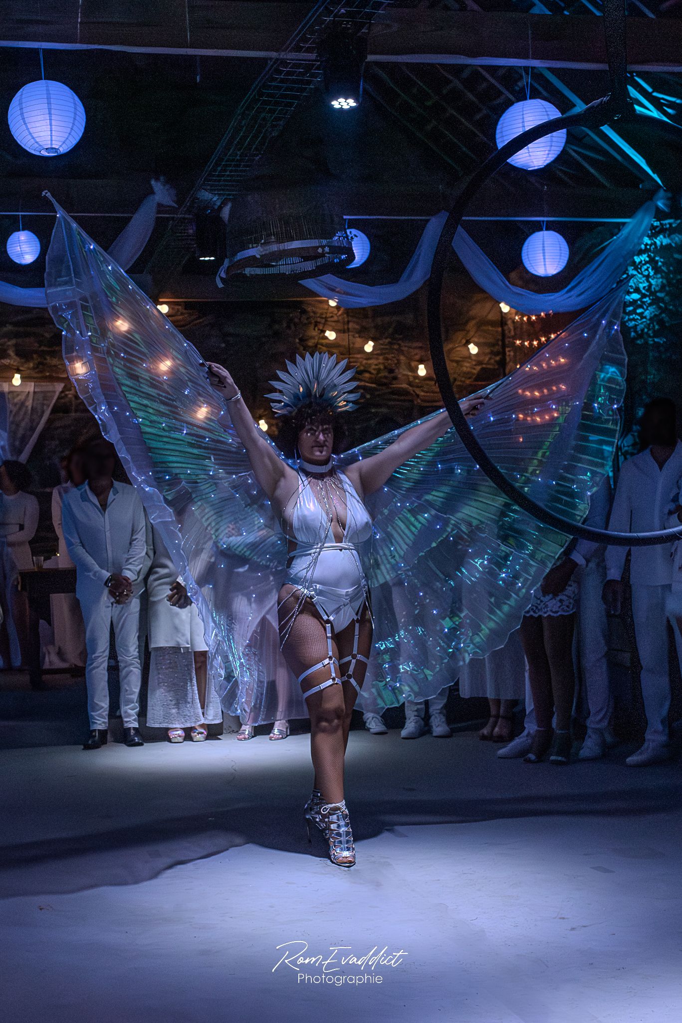 femme artiste en body blanc irisé avec ailes transparente effet écaillé, couronne de strass lors d'une soirée privée - photo événementiel