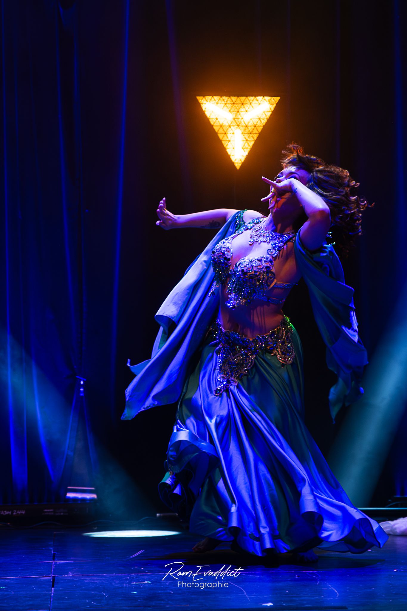 photo sur scène danseuse du ventre grande robe satinée bleu et verte - lumière colorée - photo artiste événementiel concerts spectacles