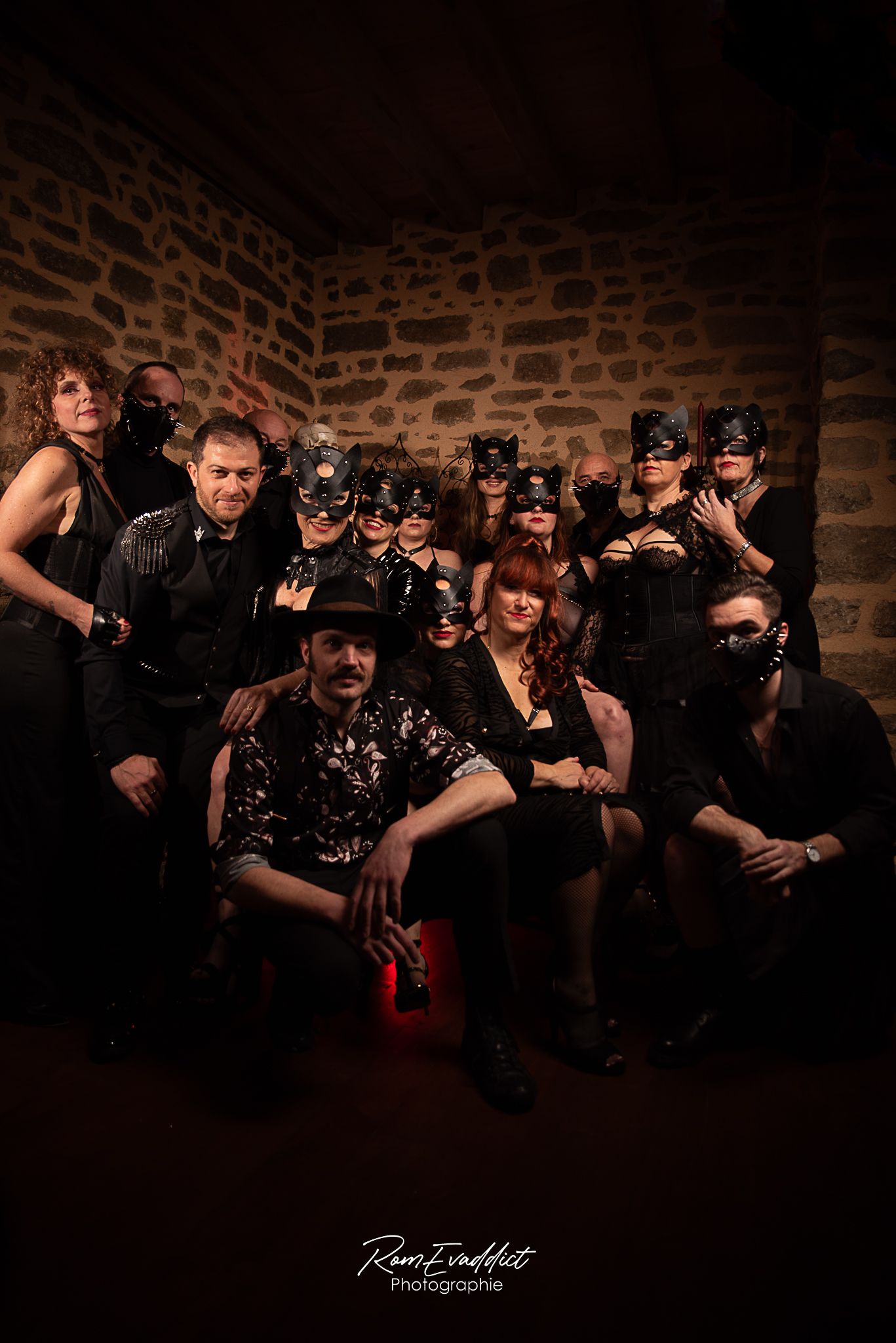 groupe d'artiste en tenues noire gothique, accessoires chaines clous masques cuir devant mur en pierre - photo troupe artiste événementiel