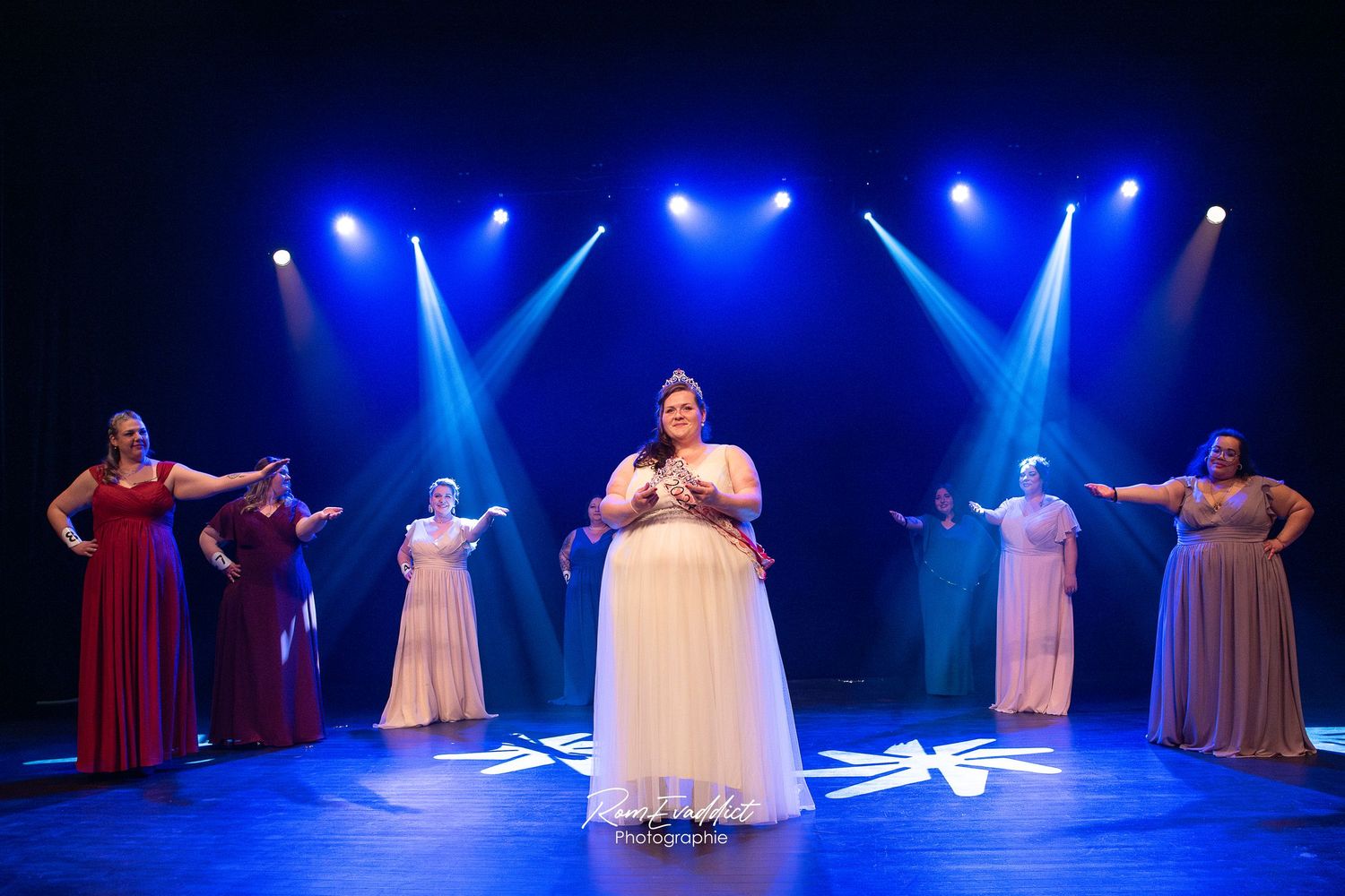 participantes miss ronde se tenant sur scène en cercle bras tendu vers la miss élue avec sa couronne en strass et sa longue robe blanche