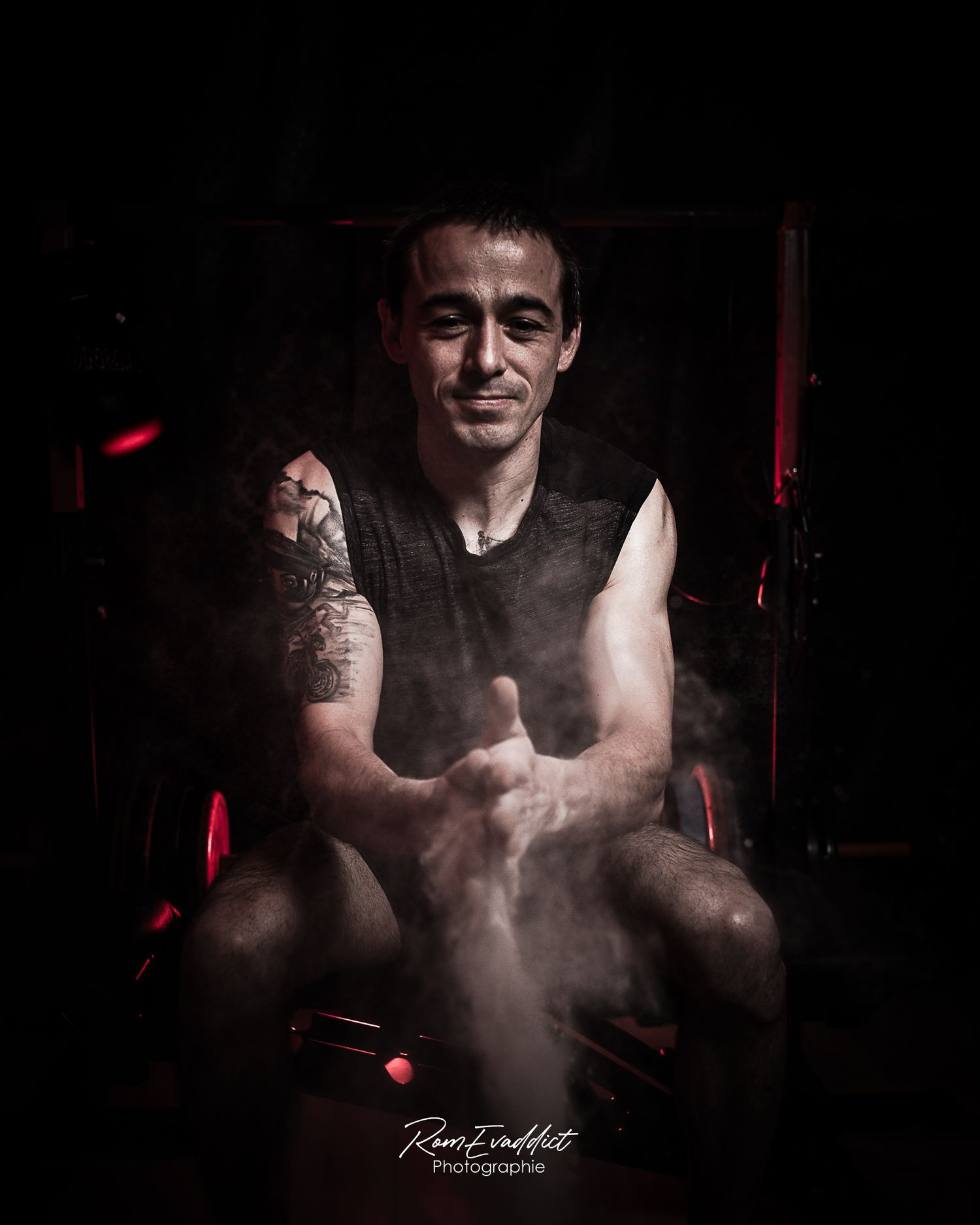 homme coach sportif en débardeur noir assis sur banc d'abdo tape dans ses mains - nuage de magnésie s'échappe- photo portrait corporate