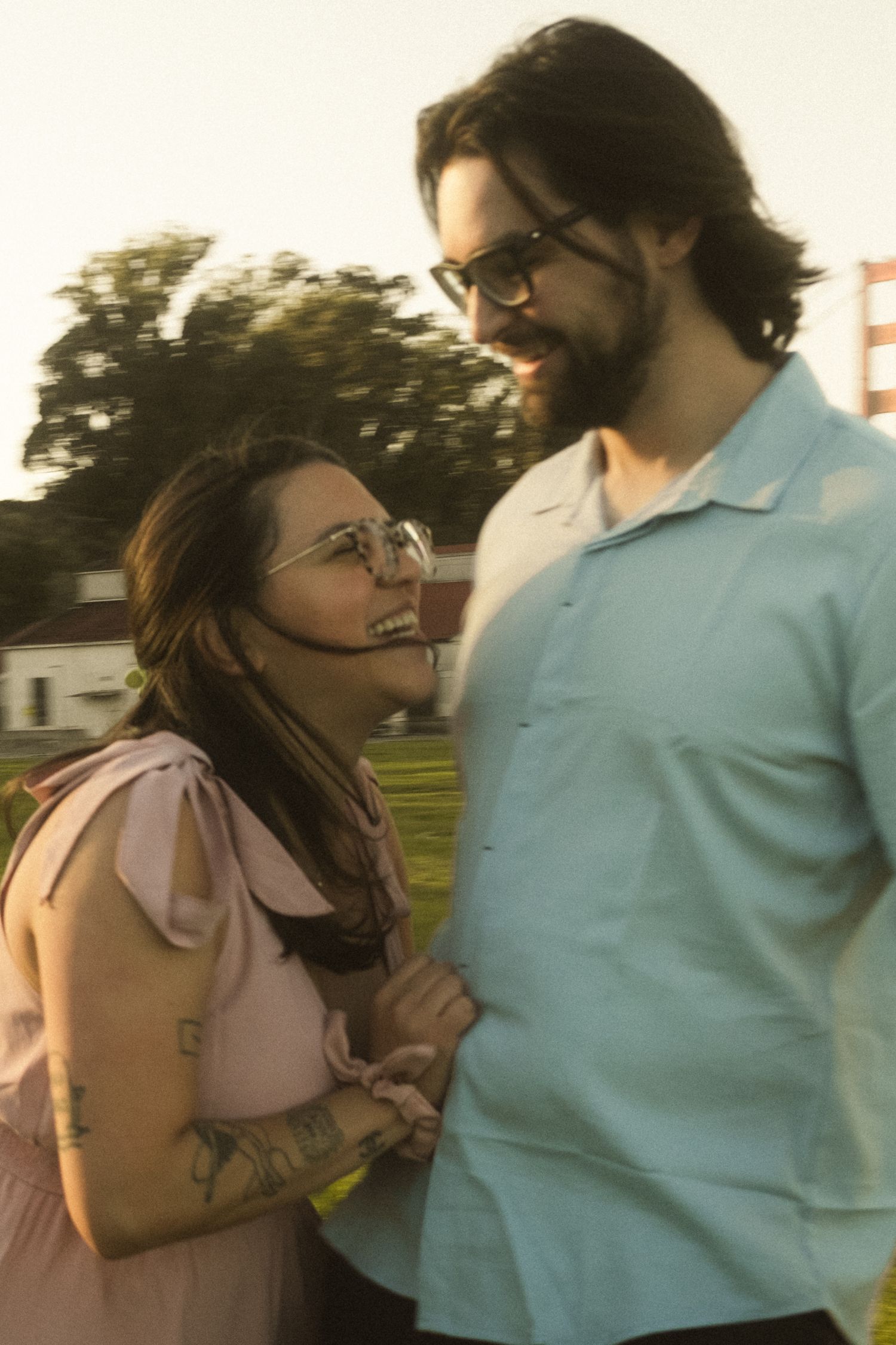 Couple sharing a playful moment in a park during golden hour.
