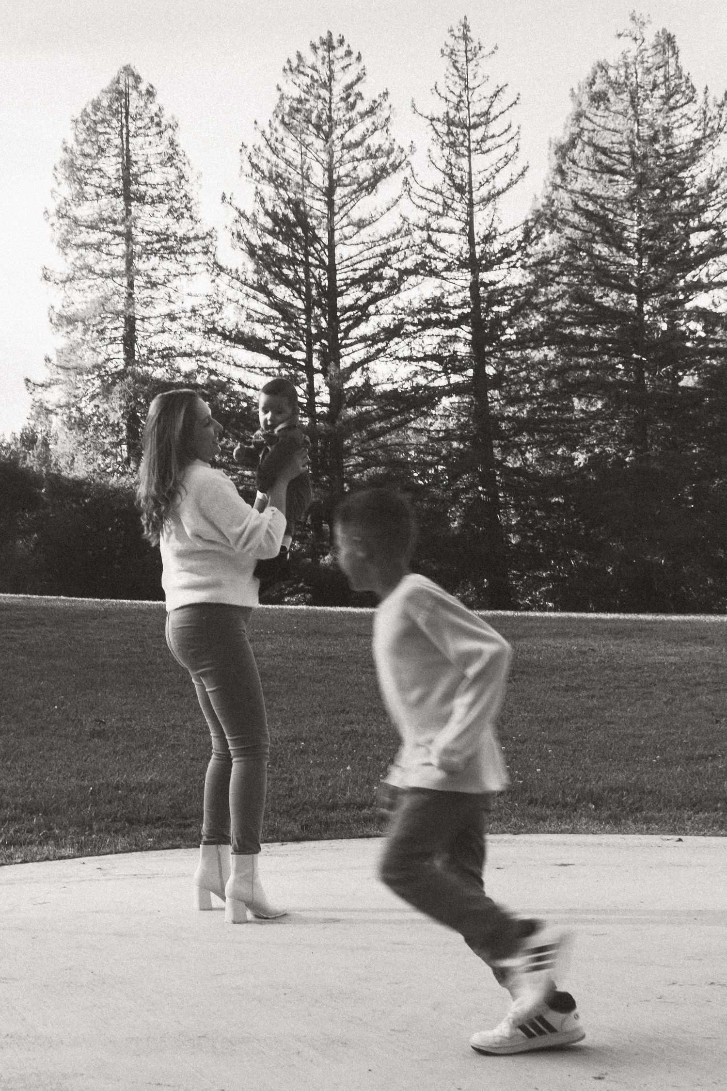 Playful sequence of figures dancing and spinning in front of evergreen trees at dusk.