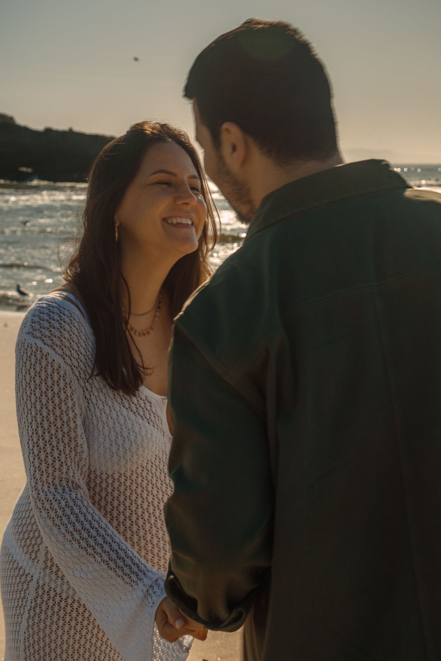 A romantic beach photoshoot sequence capturing candid laughter and joy at golden hour.