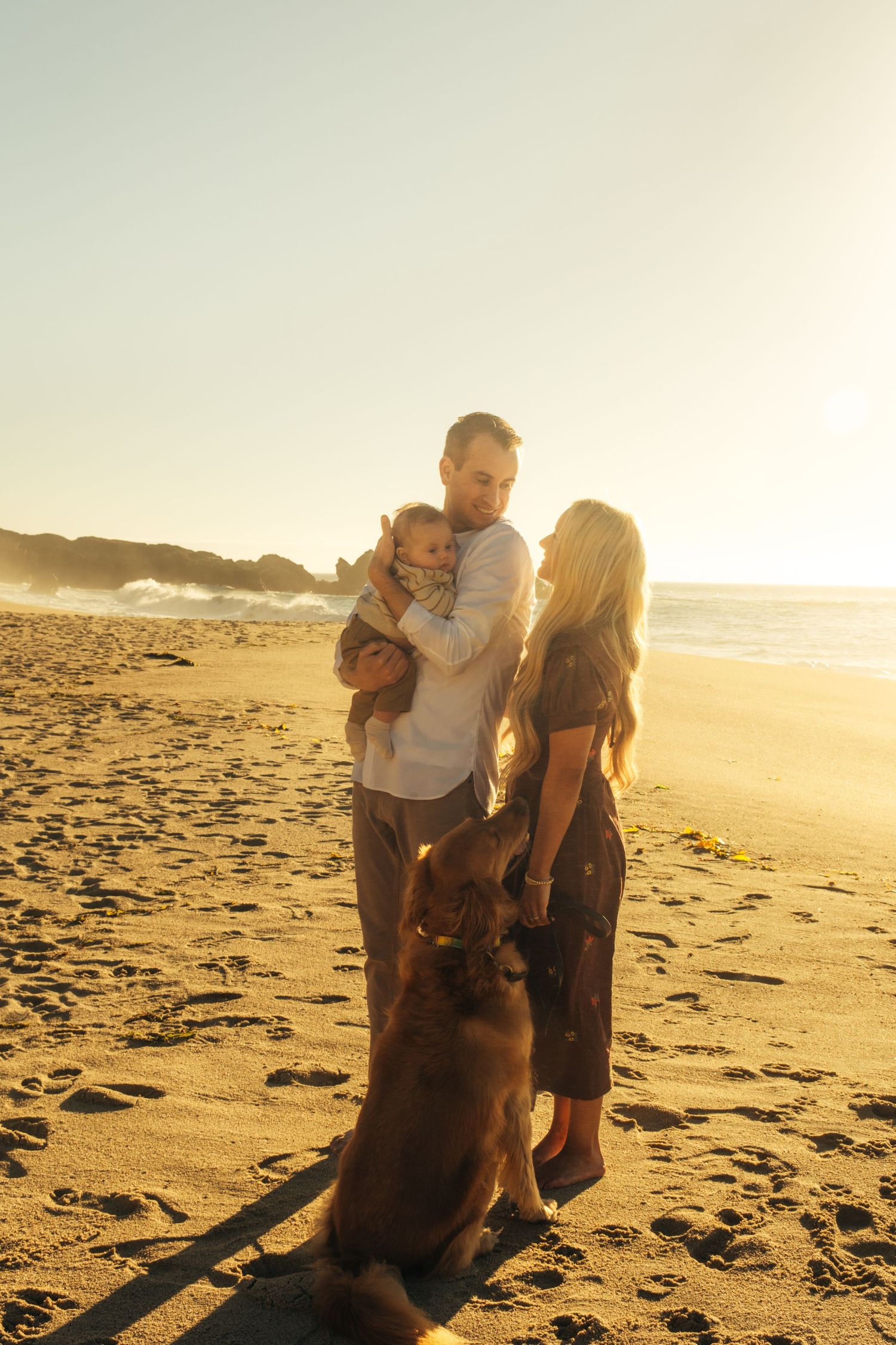 A family enjoys quality time together on a sandy beach at sunset.