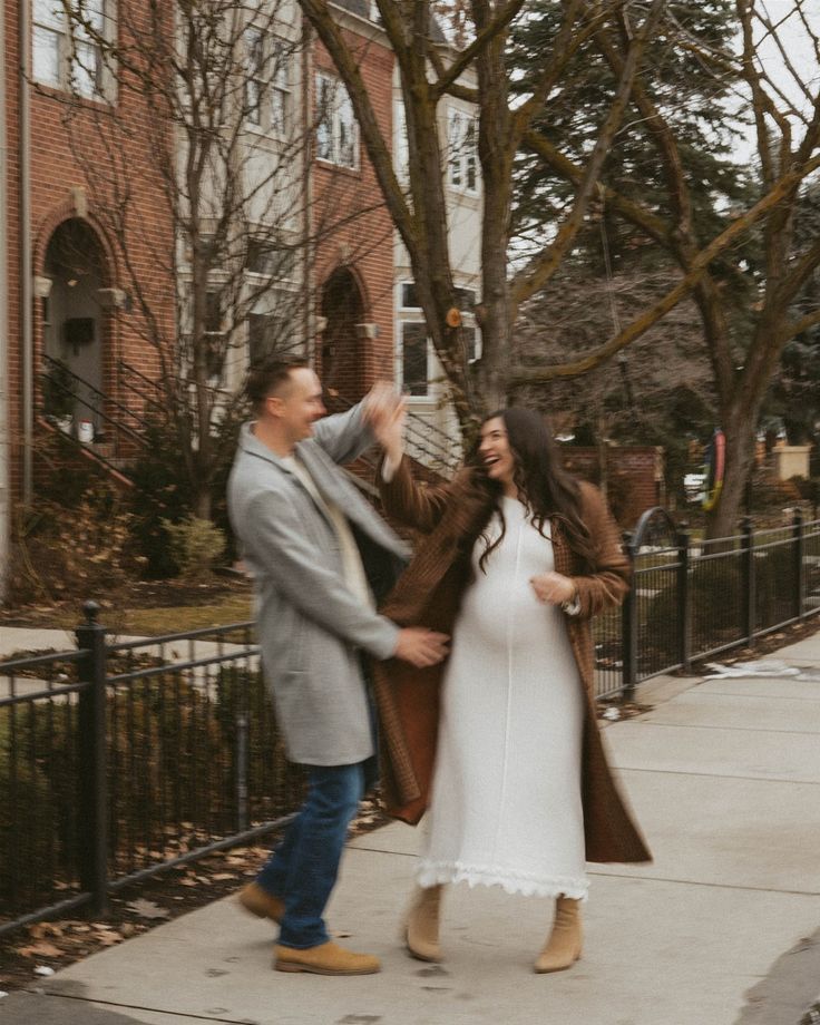 Romantic winter photoshoot on a tree-lined sidewalk with brick buildings in background.
