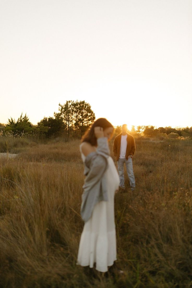 Romantic sunset photoshoot of couple in a golden field with long grass and warm lighting.