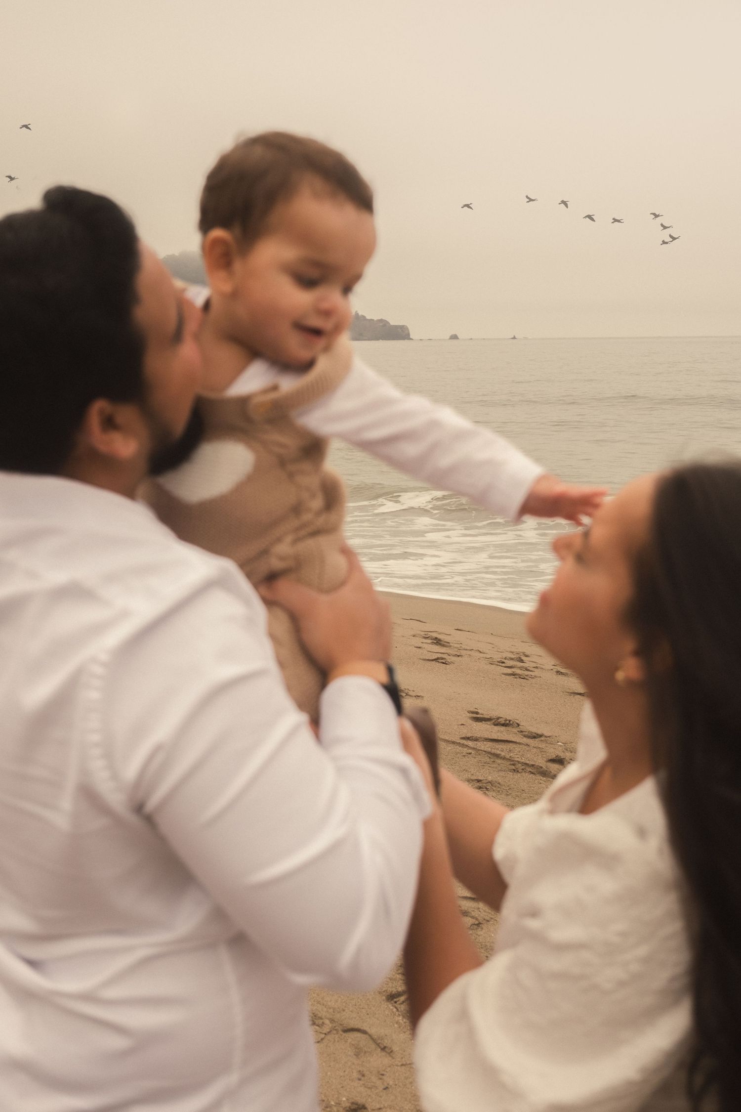 A playful family moment captured on a misty beach.