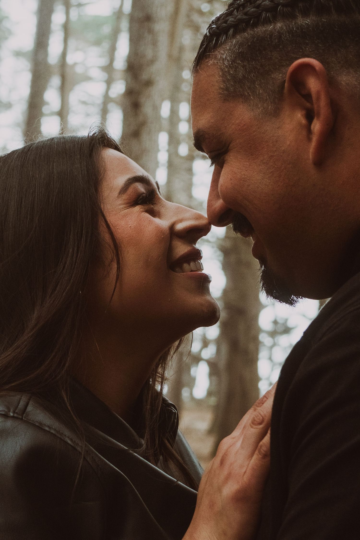 Intimate forest portrait of couple in winter coats with soft lighting.