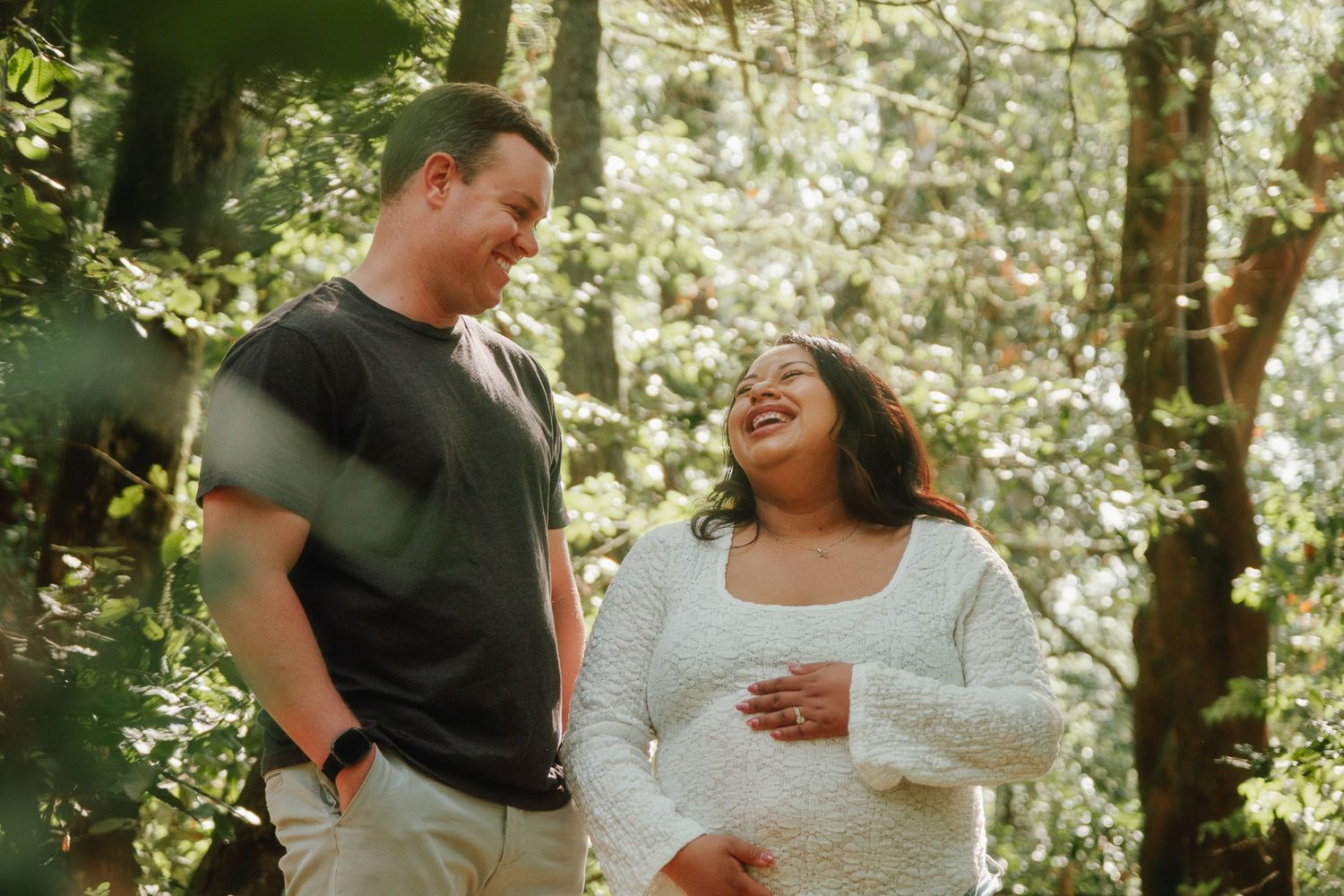 Couple sharing tender moments in dappled forest sunlight.