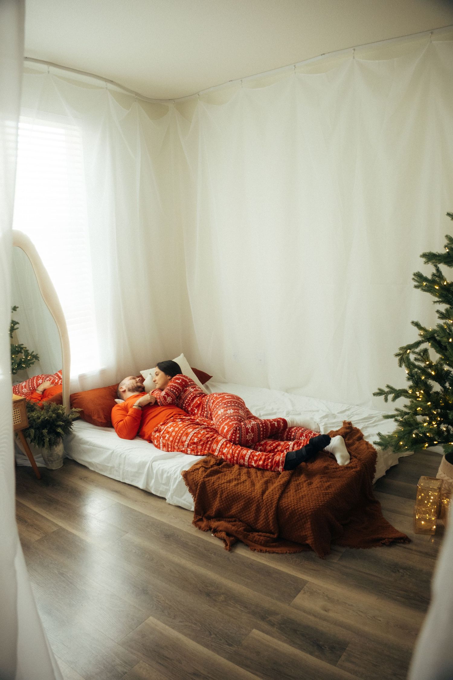 A bedroom scene with red holiday pajamas, white bedding, and Christmas decorations.