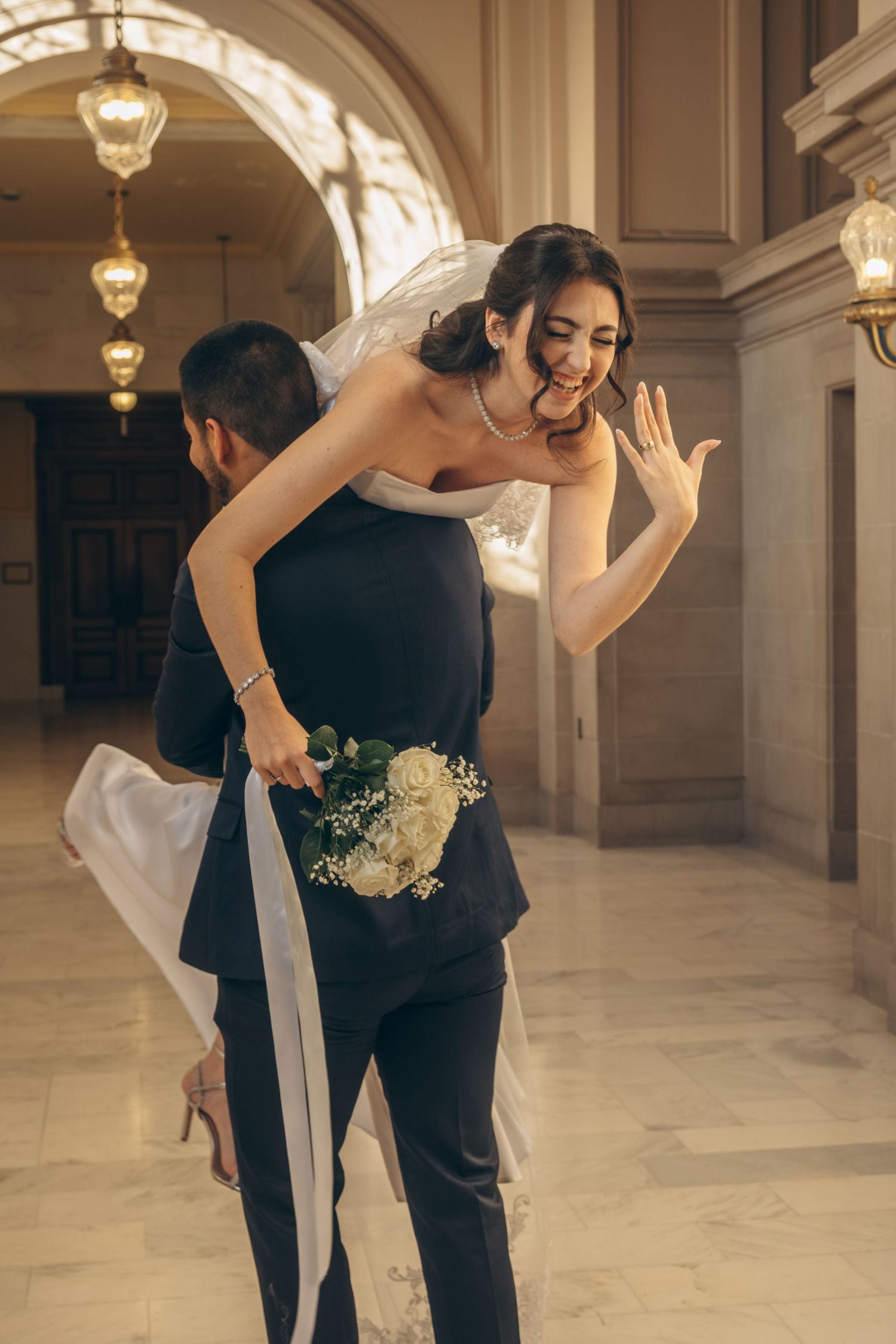 Newlyweds sharing playful moments in an elegant arched hallway.