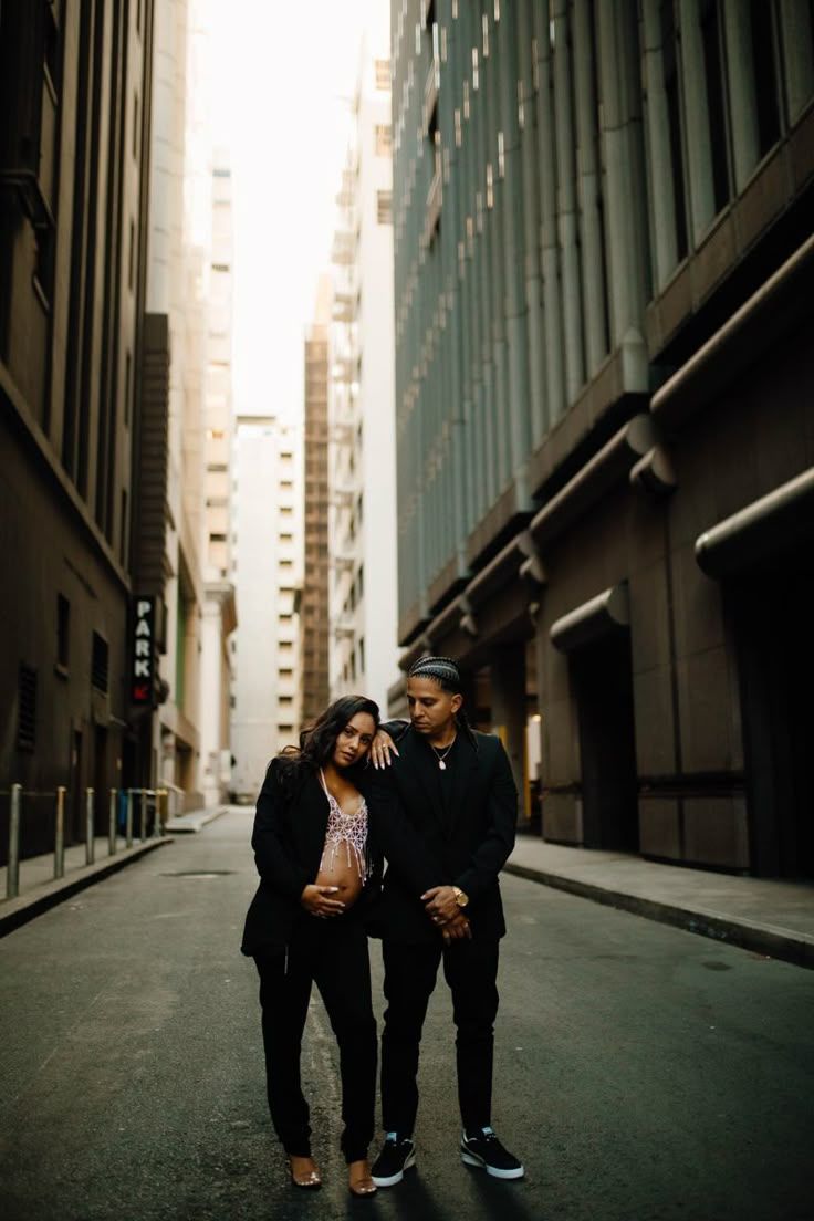 Stylish urban couple photography in dramatic city alleyway with tall buildings.