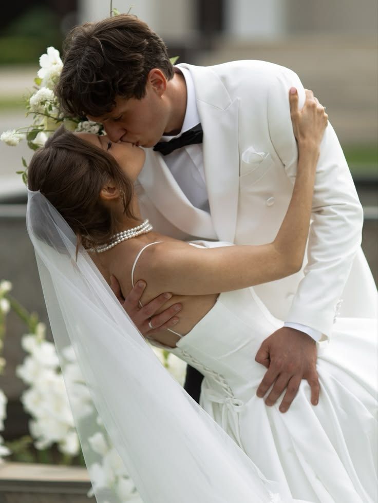A romantic wedding moment captured as newlyweds share a passionate kiss in traditional white formal attire.