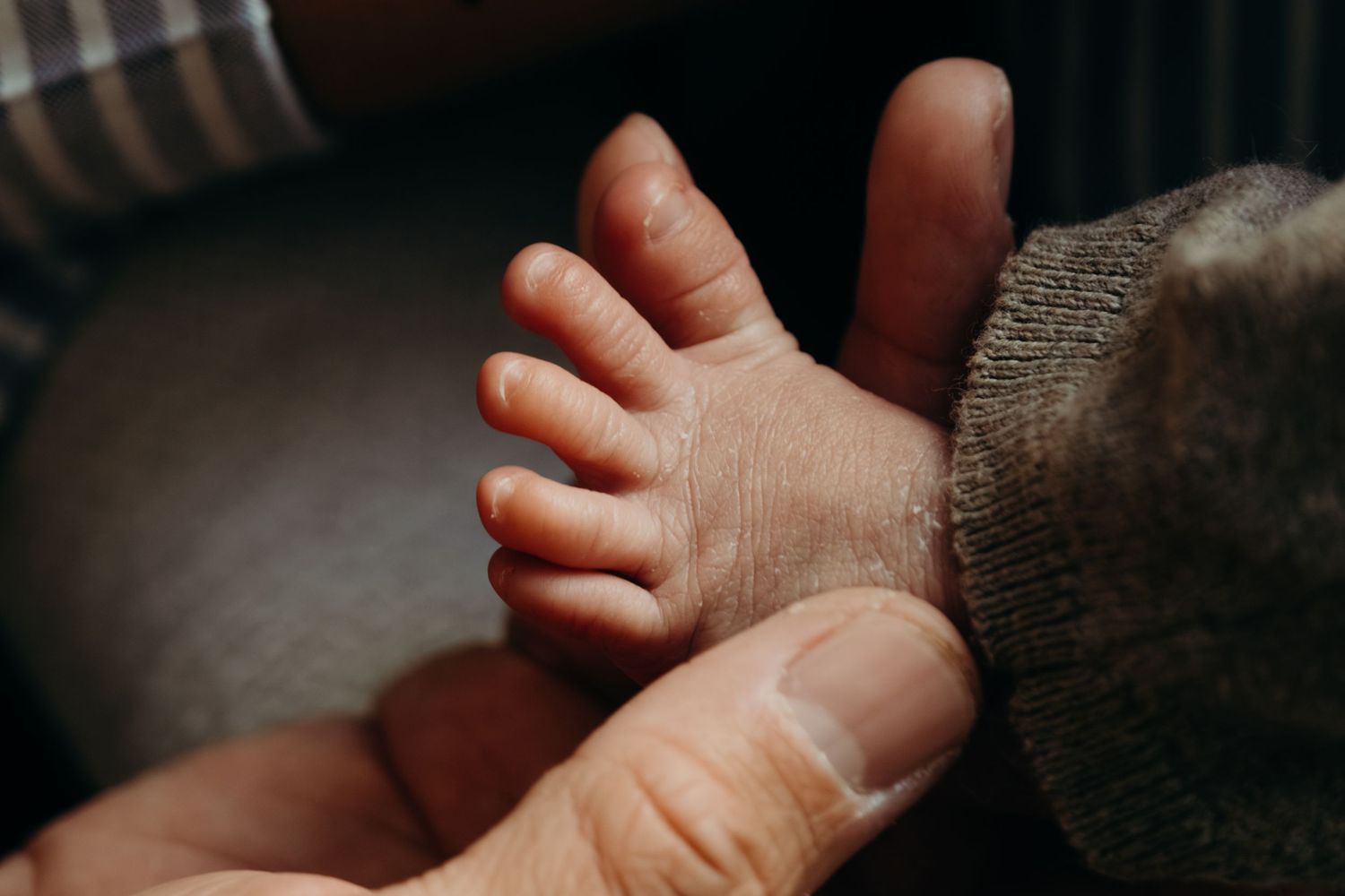 Close-up of a newborn baby's tiny foot resting gently in an adult's hand.