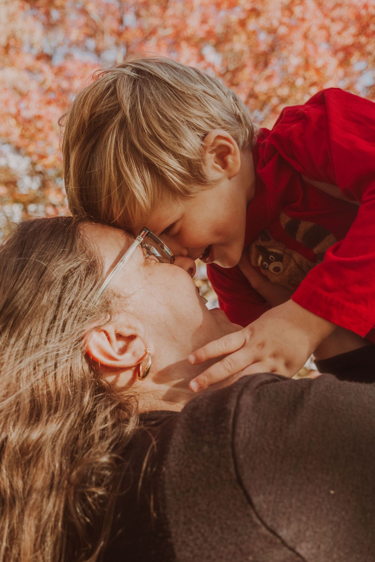 A tender moment captured in warm autumn lighting with fall foliage in the background.