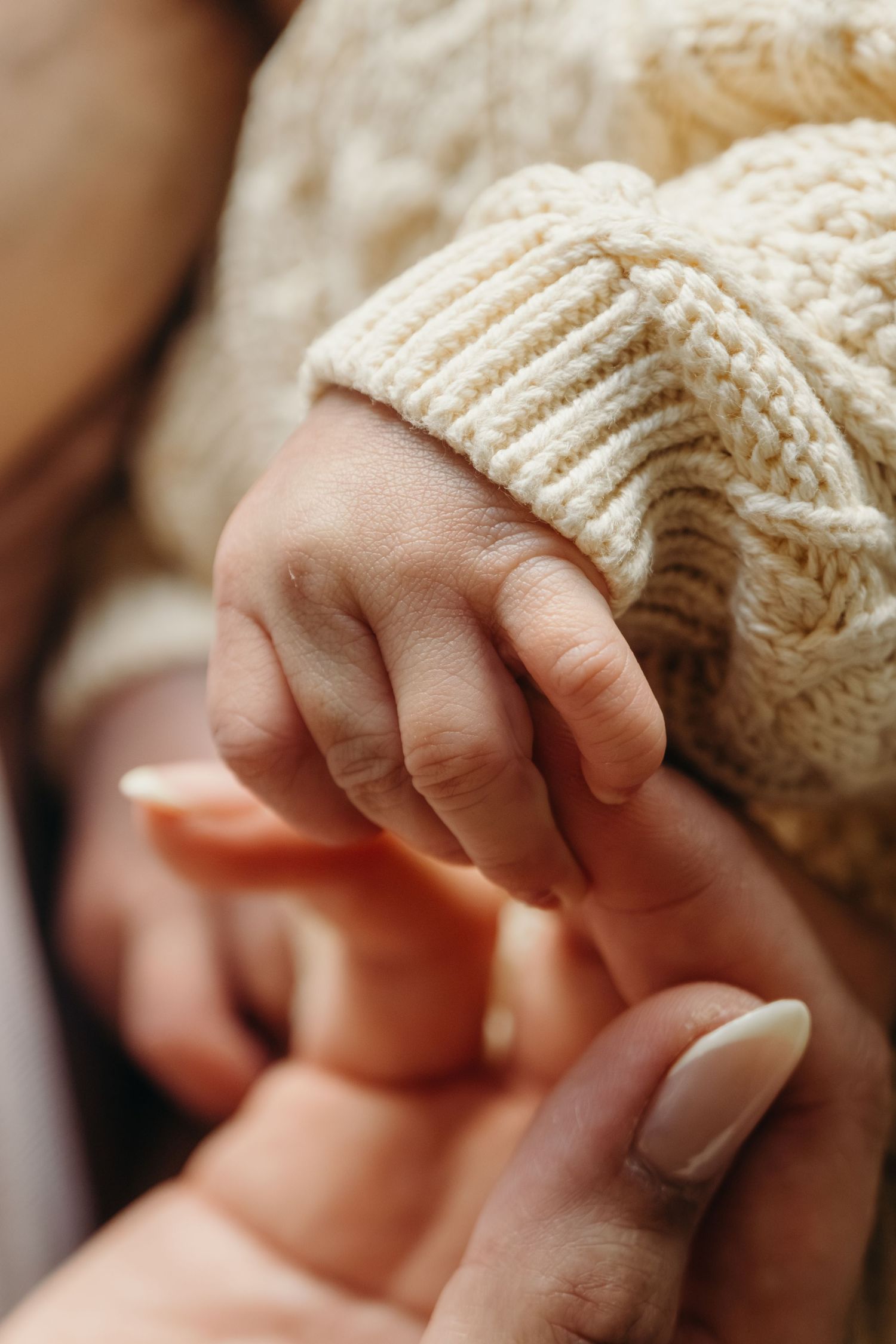 Close-up of tiny fingers grasping a white knitted material.