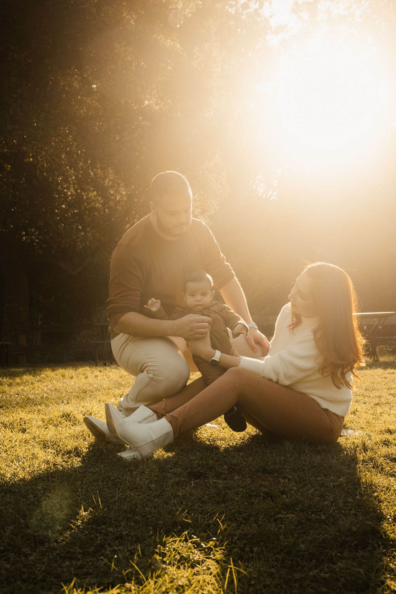 Family relaxing together on grass during golden hour sunset.