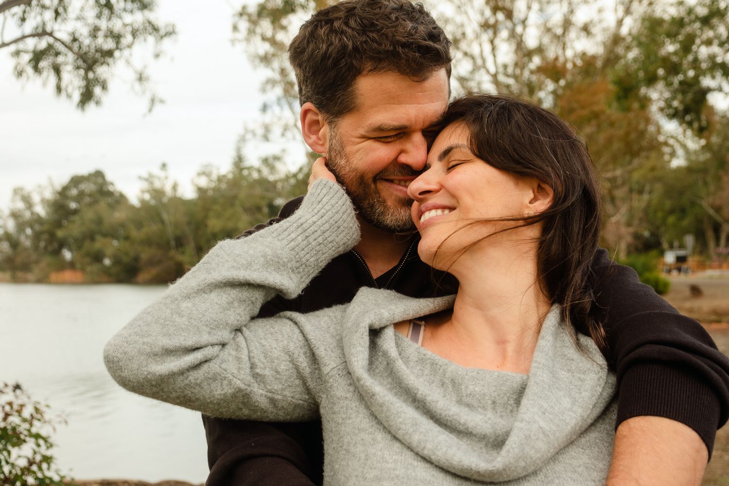 Romantic couple sharing intimate moments in a natural outdoor setting during golden hour.