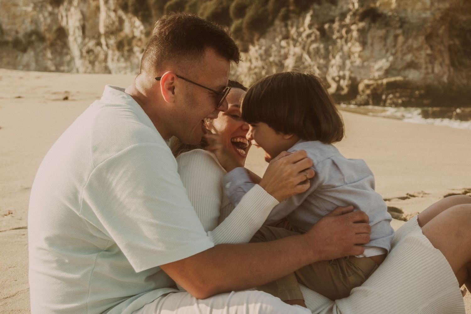 Sequence showing couple embracing on beach with cliffs in background.