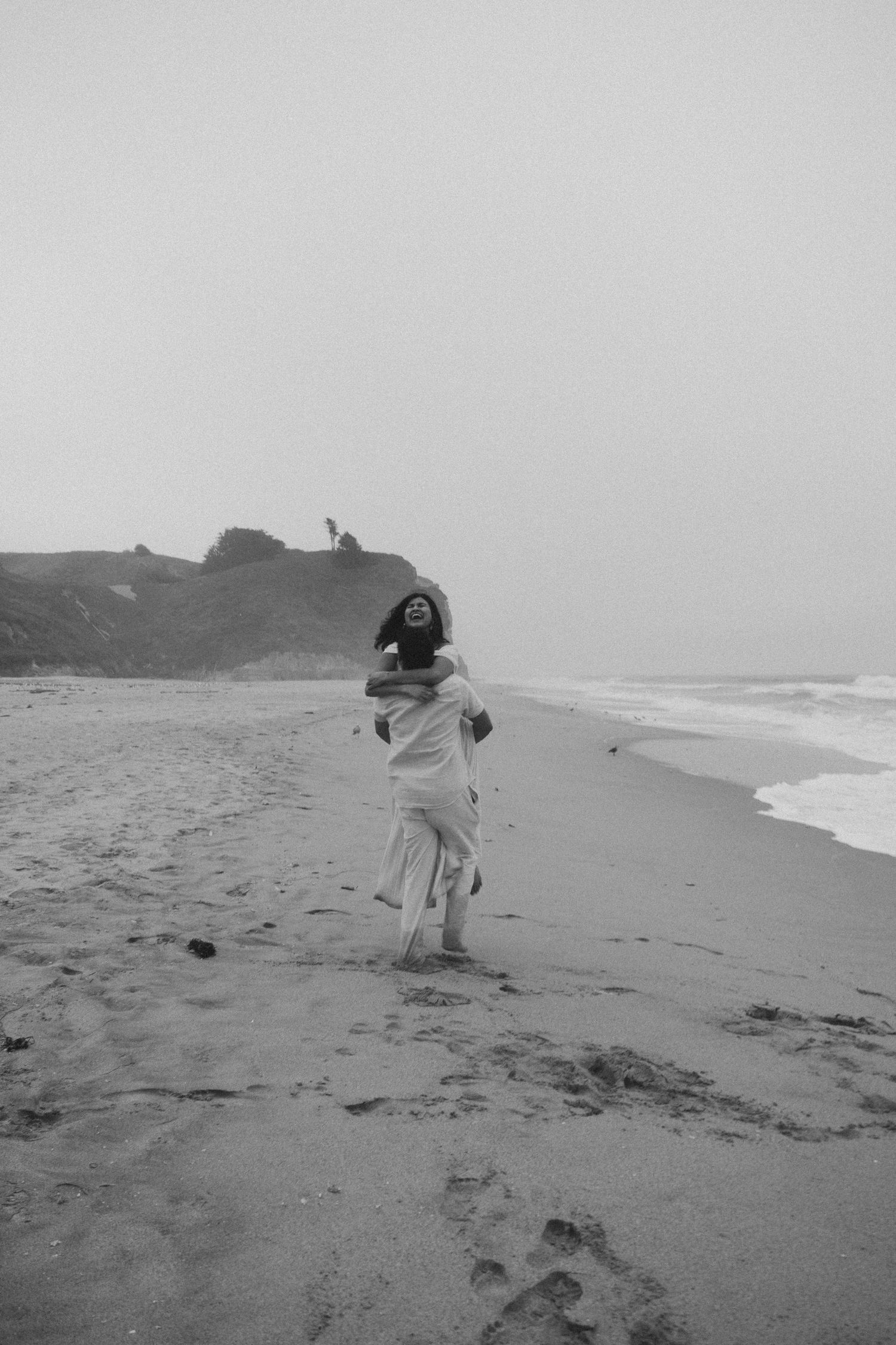 A person in a flowing white dress dances on a foggy beach.