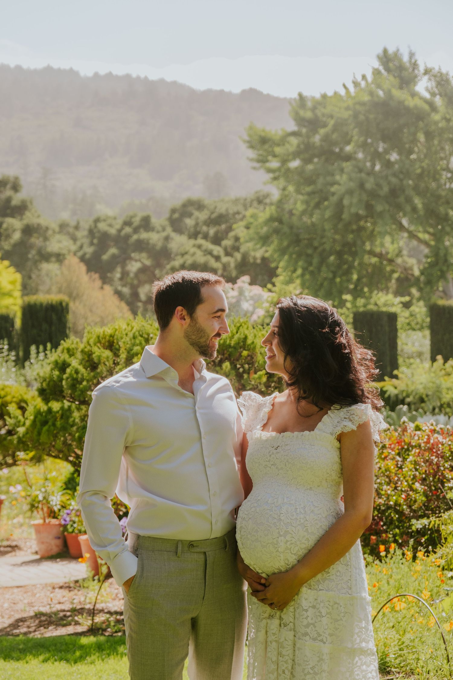 Romantic garden photoshoot with couple in white and beige attire.