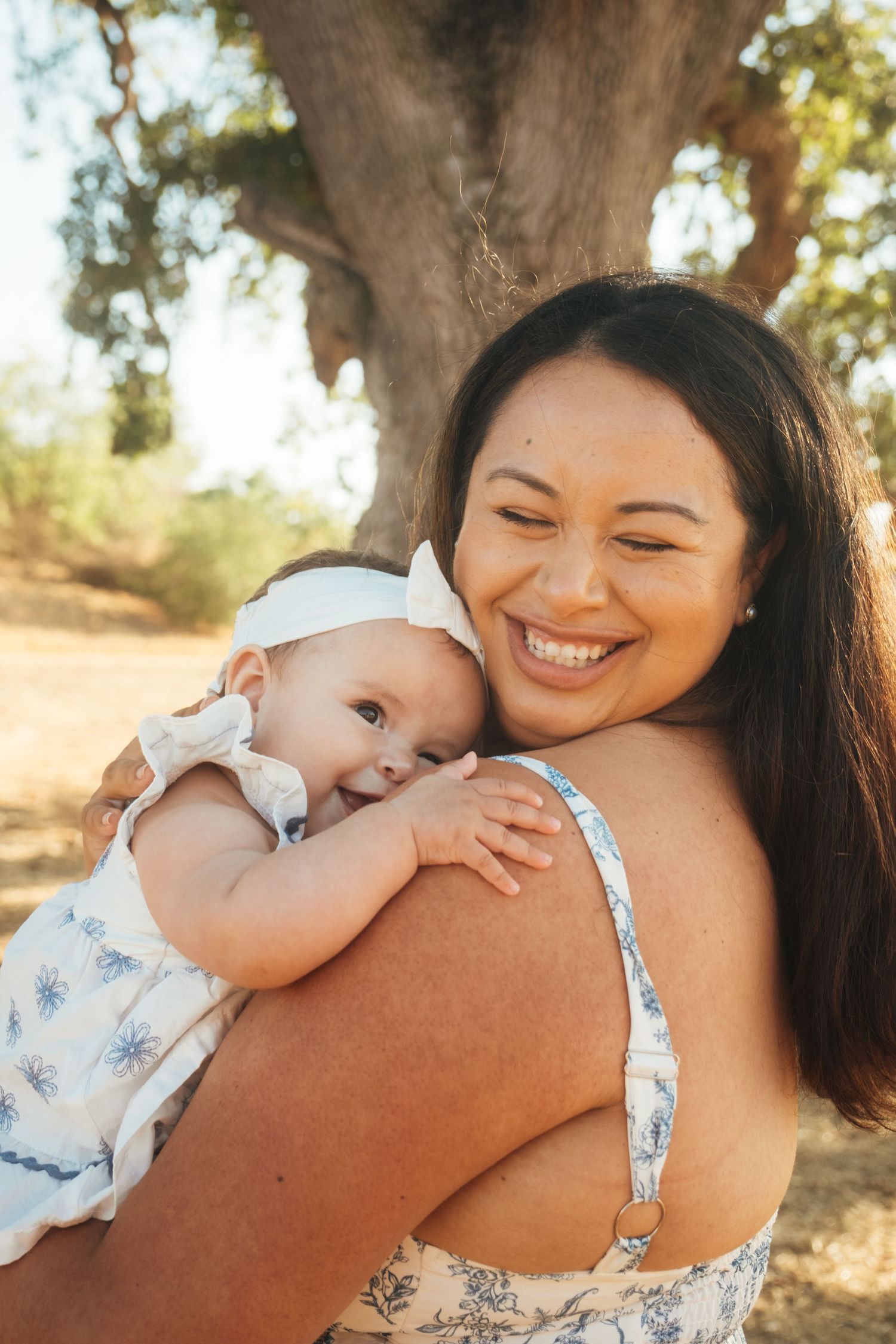 A tender moment of affection and laughter shared between parent and baby outdoors.