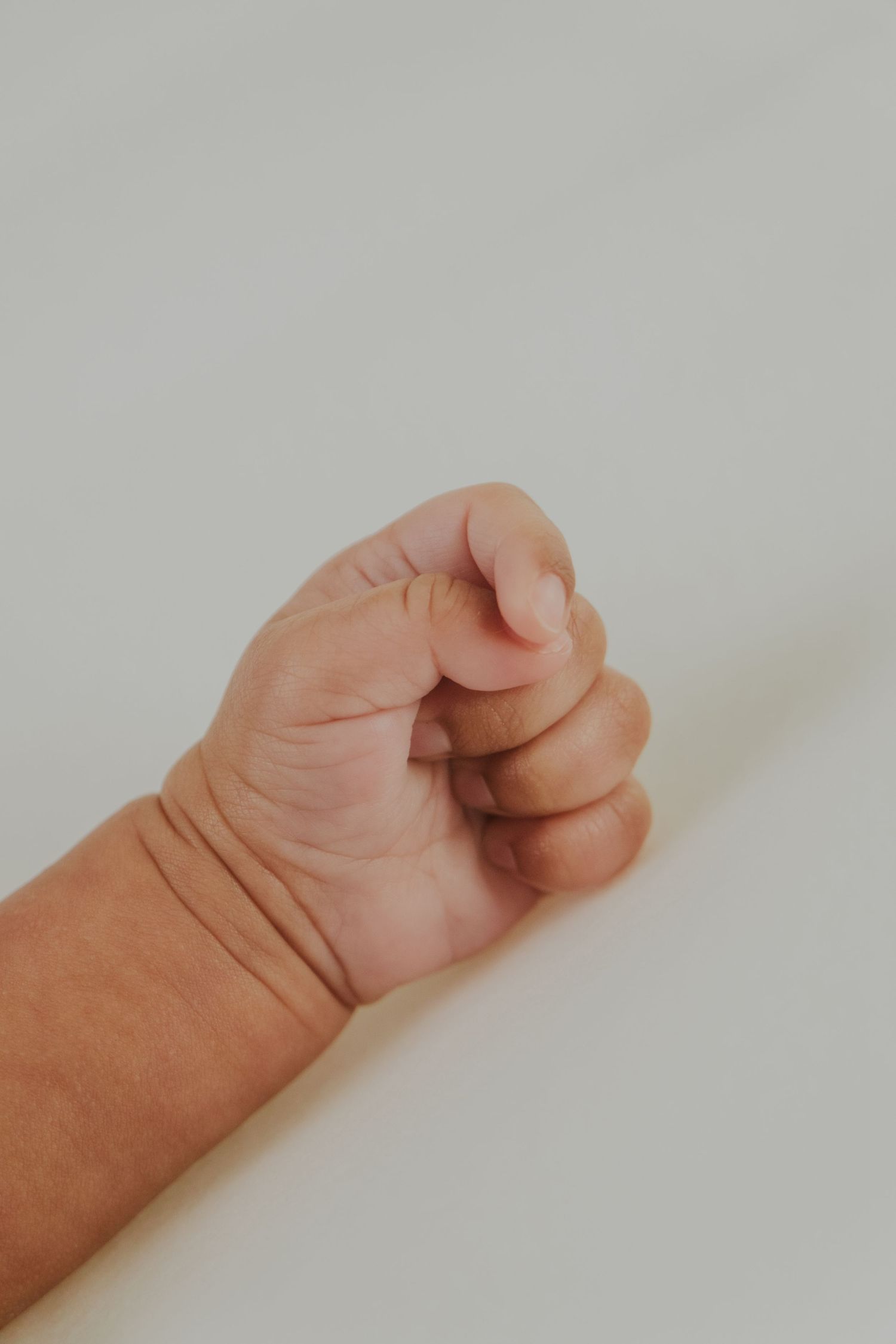 Close-up of a small baby's hand curled into a gentle fist.