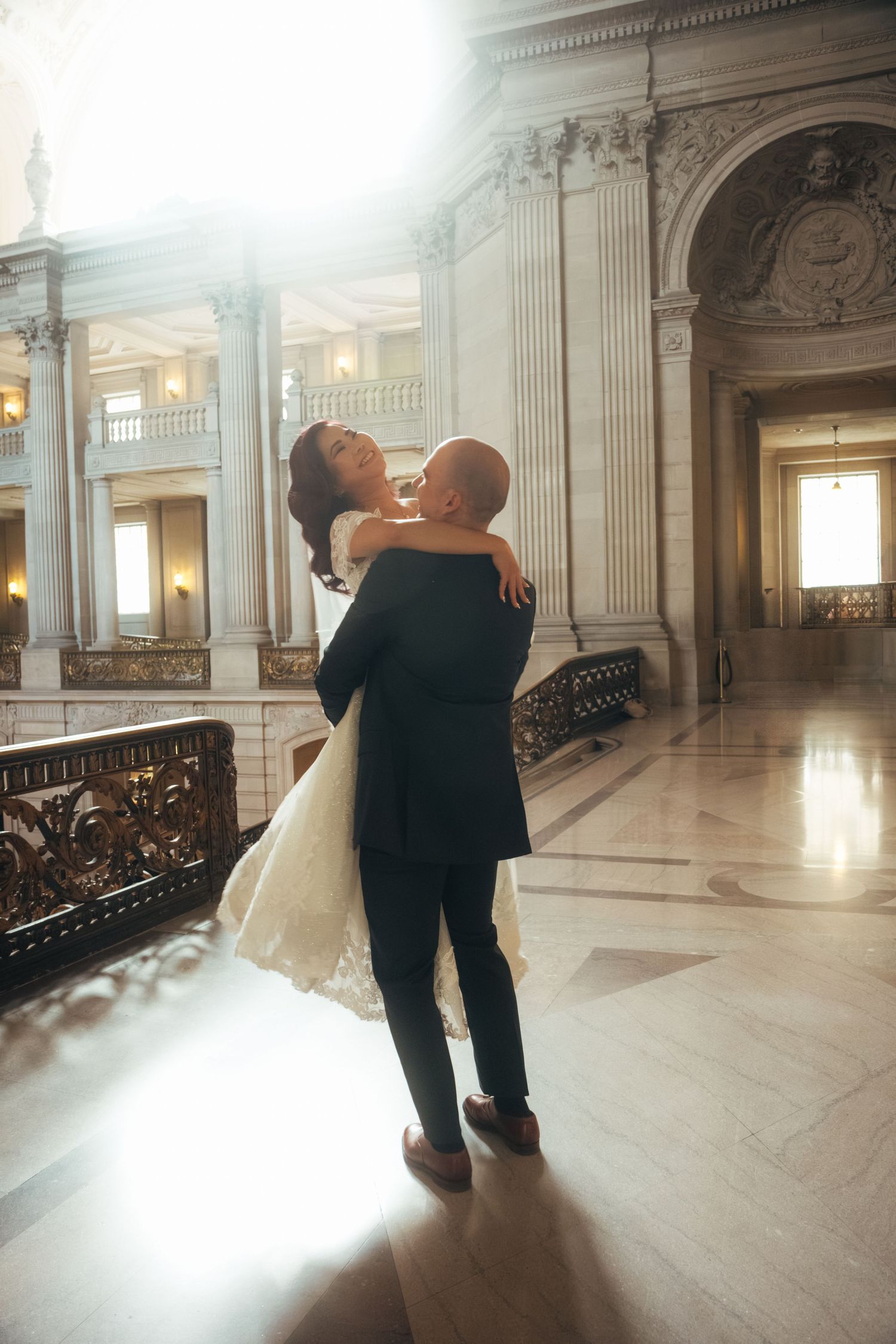 Dancing newlyweds in a sunlit marble hall with classical architectural details.