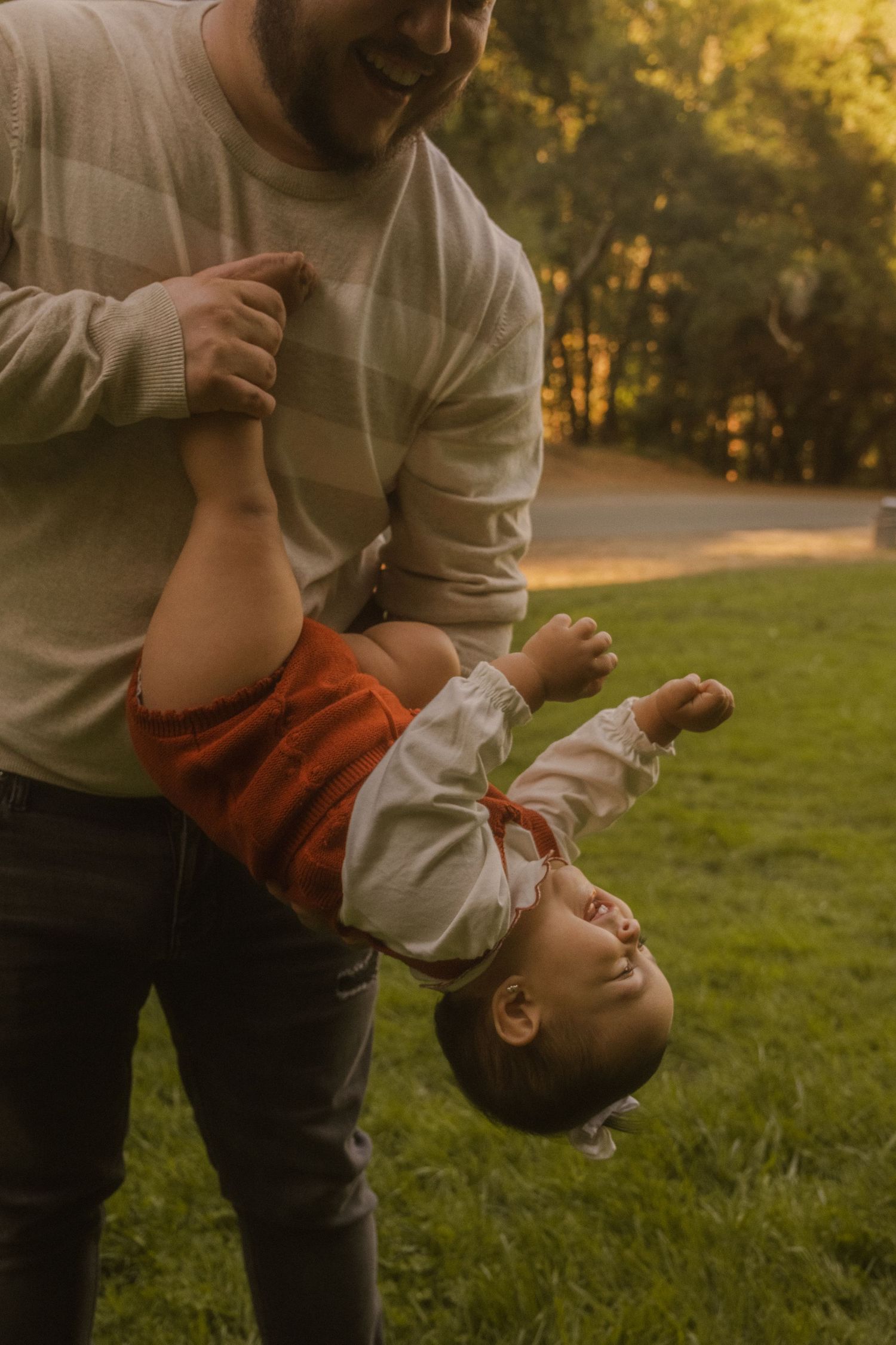Playful family moment captured at sunset in a grassy field.