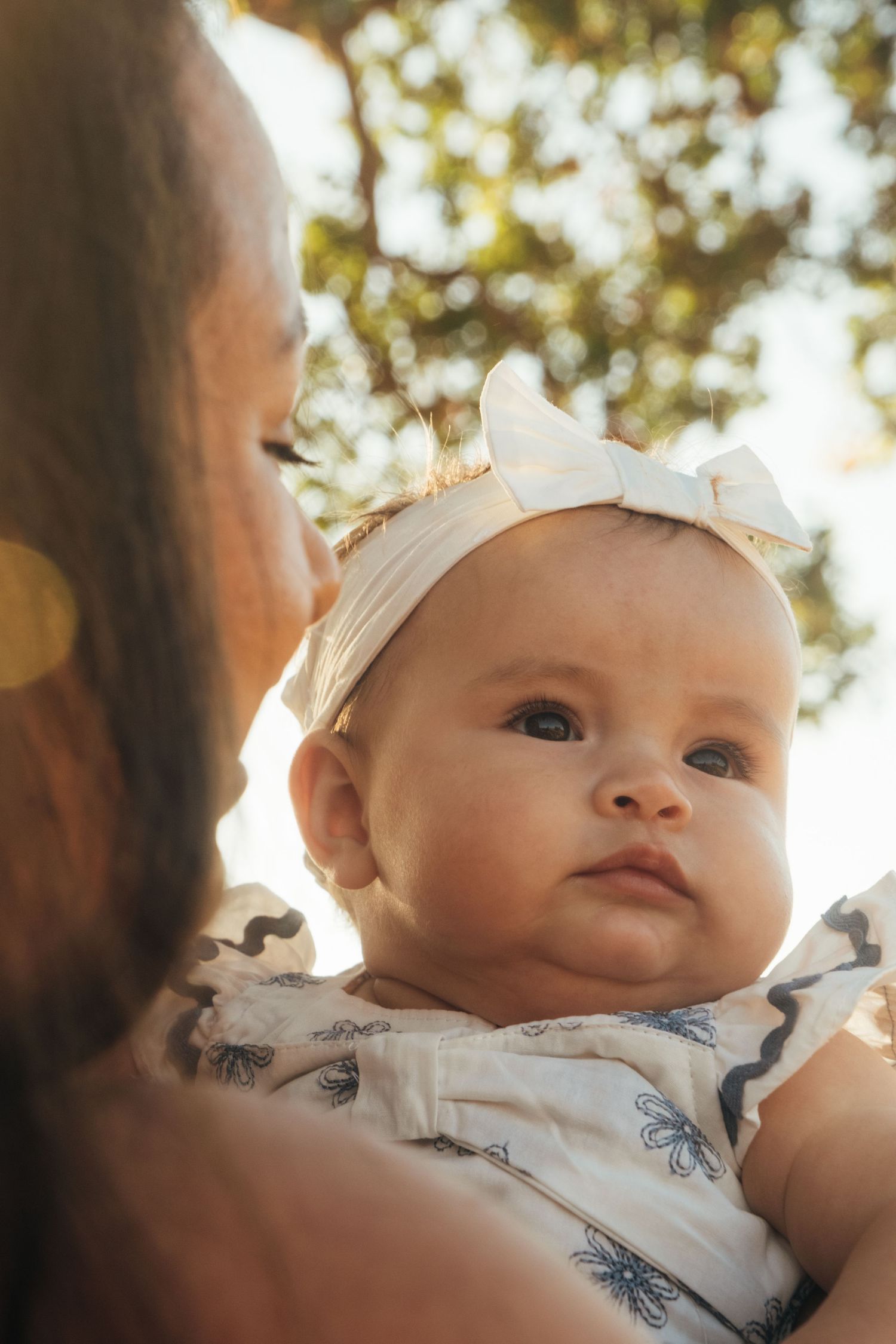 Close-up portrait of an adorable baby wearing a white bow headband.