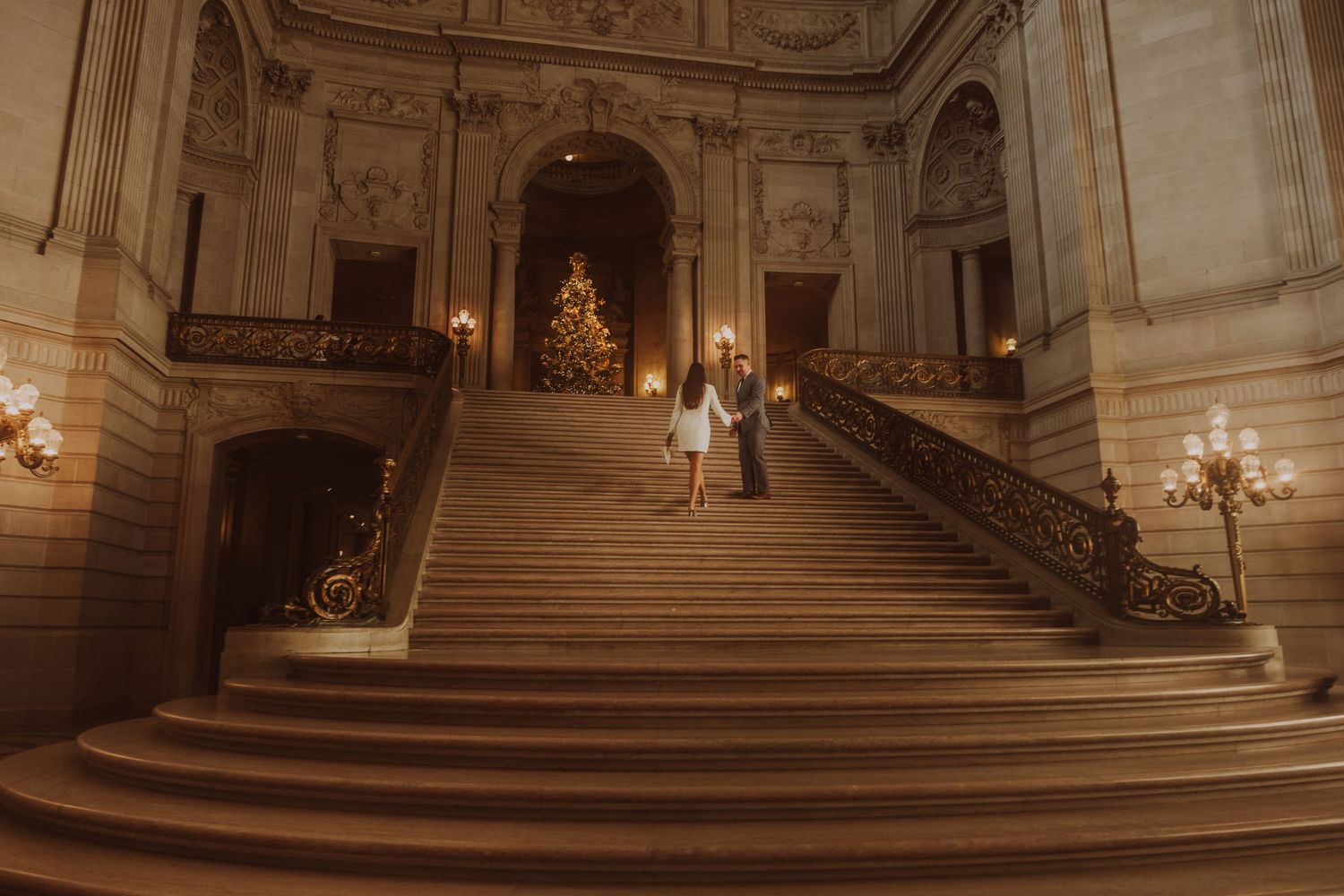 Elegant marble staircase inside City Hall illuminated by warm lighting and chandeliers.