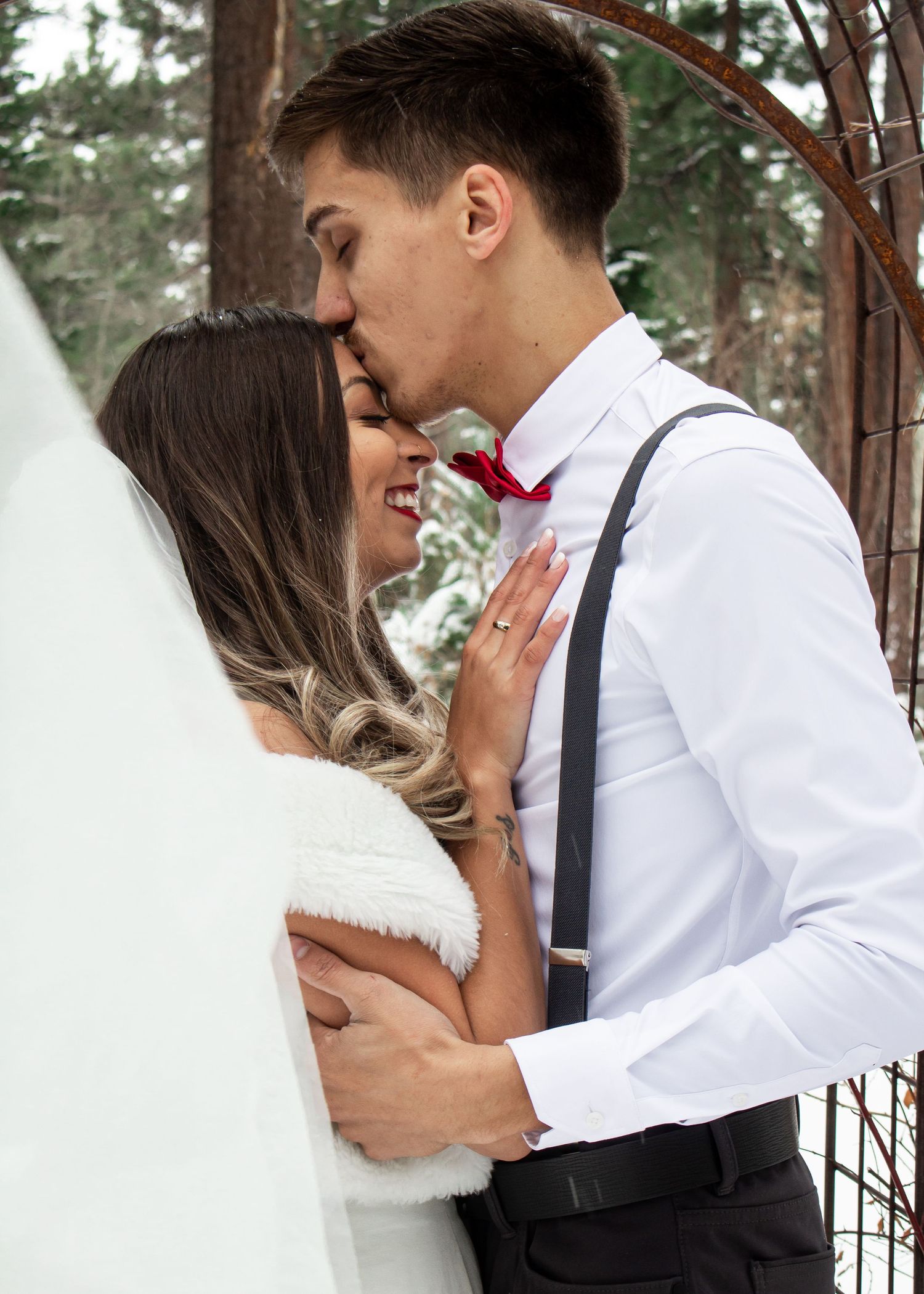 A tender winter wedding embrace between a couple in white and formal attire.