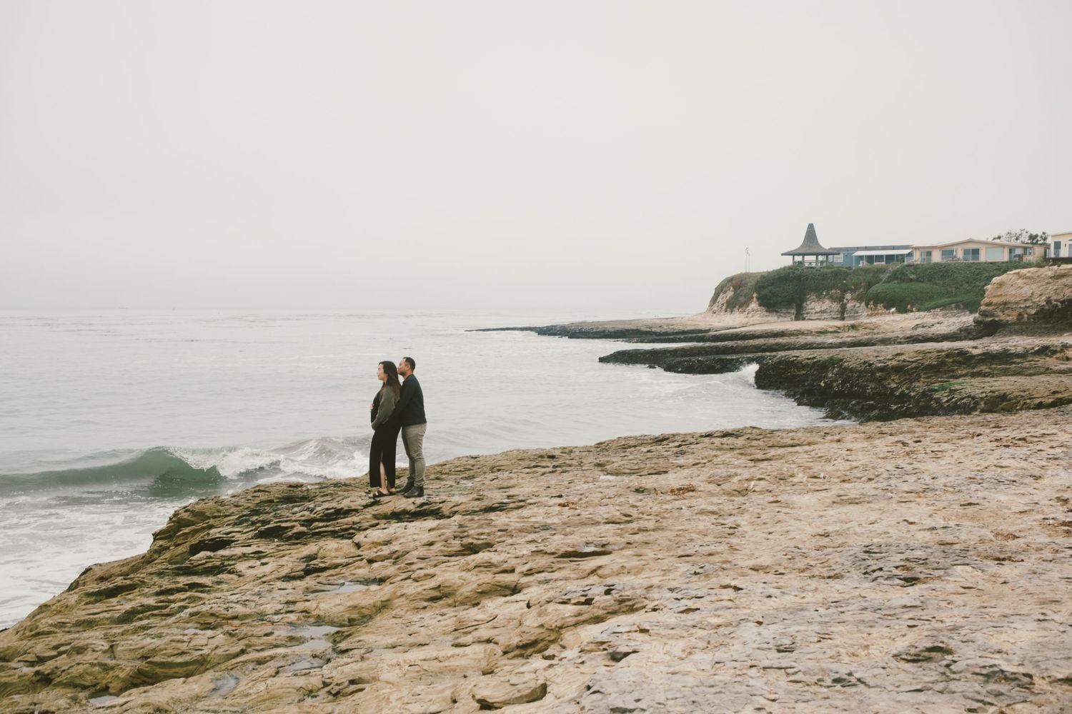 Silhouettes of people walking along a scenic coastal cliff during sunset.