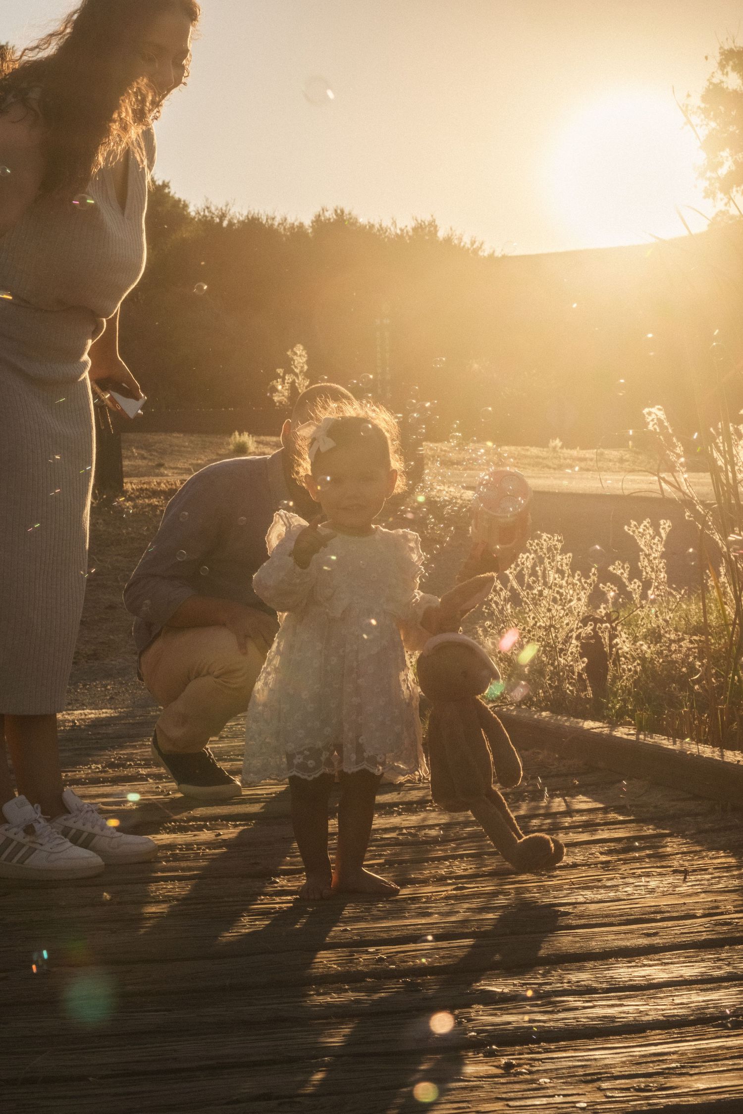 Family enjoying playful moments on wooden deck during golden hour.