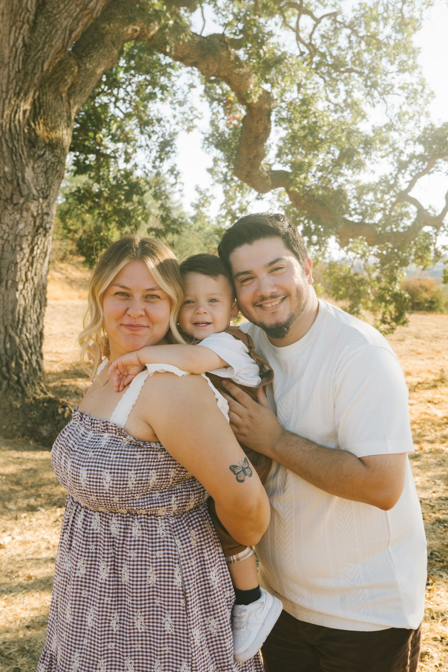 Candid family portraits captured under tree branches in warm afternoon light.