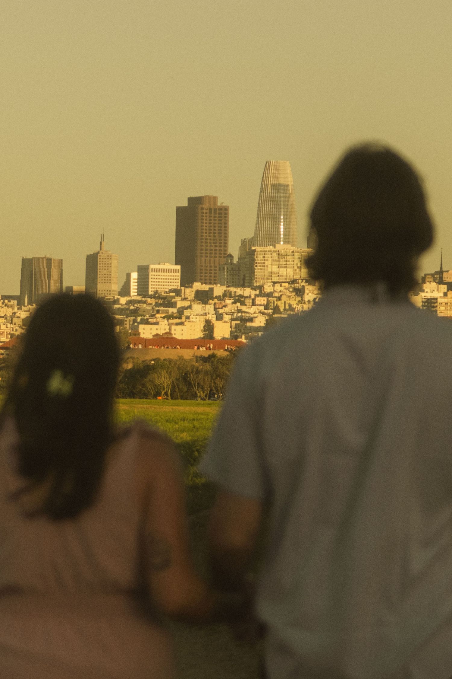 Silhouettes of a couple against a golden city skyline at sunset.