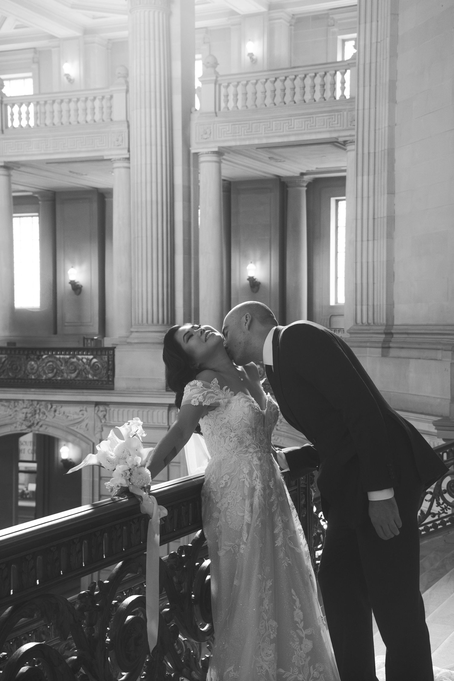 Wedding couple shares tender moments in an elegant marble hallway with classical columns.