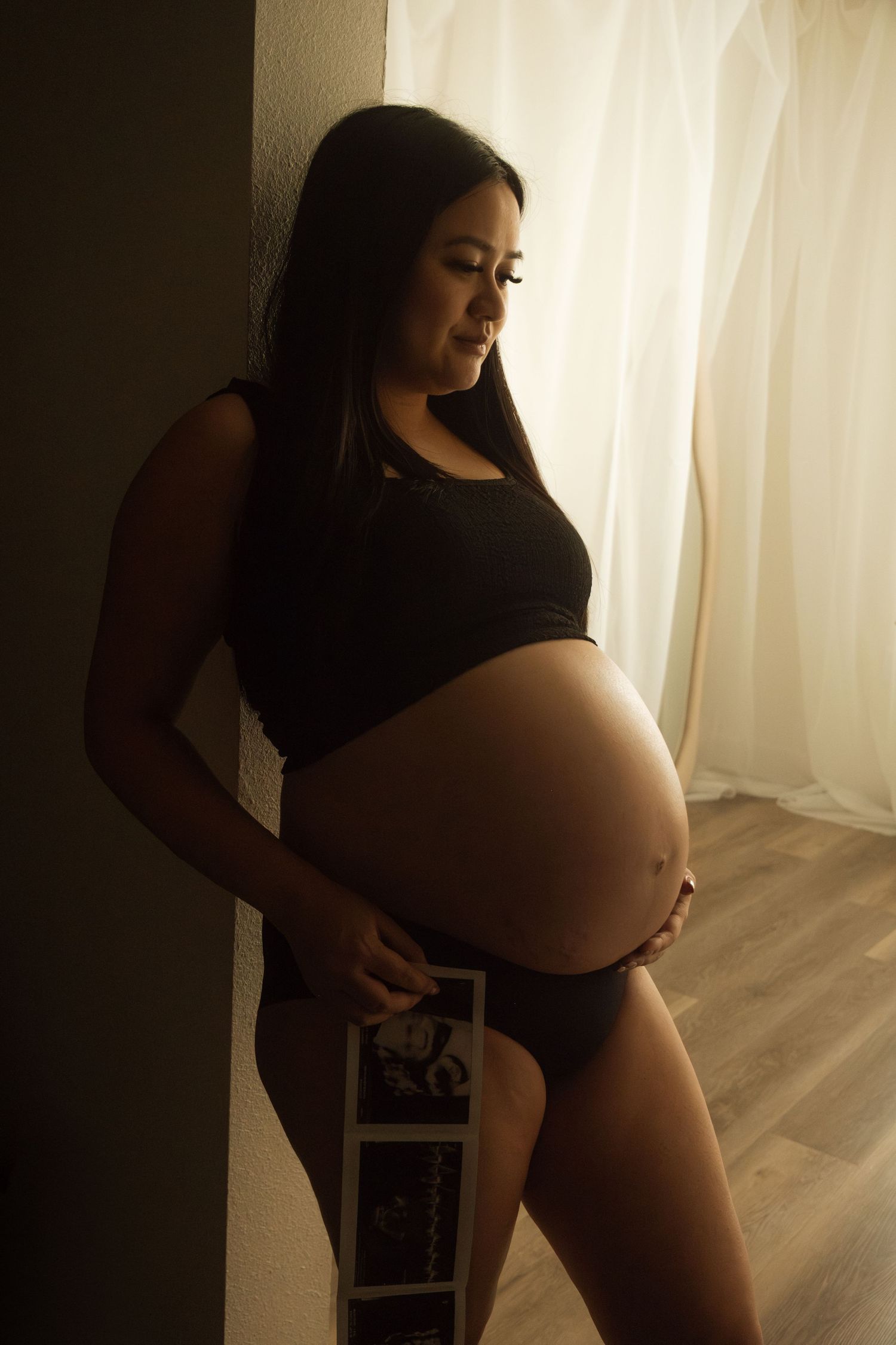 Artistic maternity silhouette photos against bright window with flowing curtains.