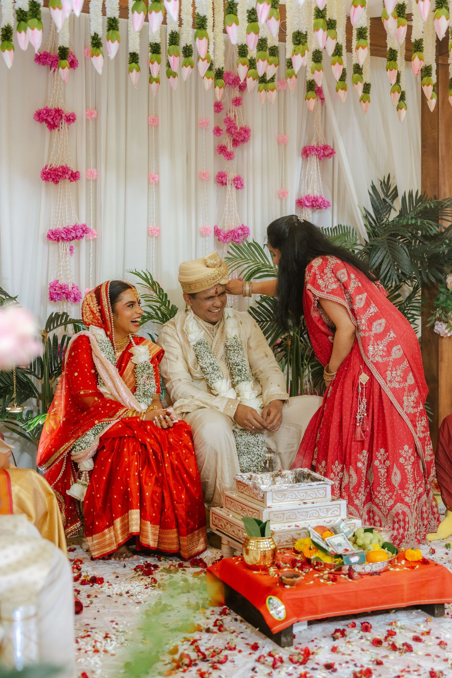 Indian bride and groom in traditional red and white attire during a vibrant Hindu wedding ceremony with floral decorations.